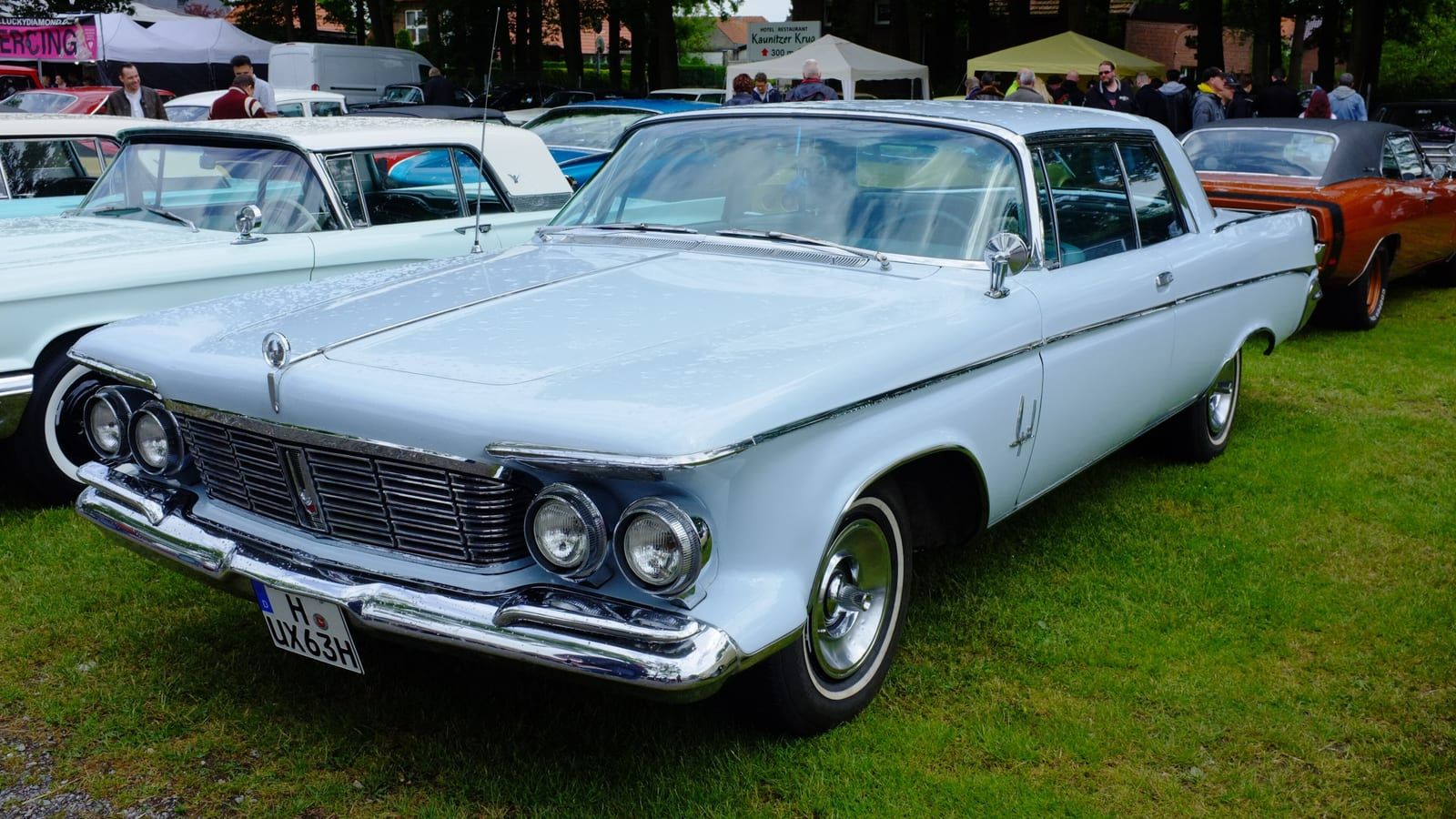 Pale blue 1963 Imperial coupe on grass, front three-quarter view.