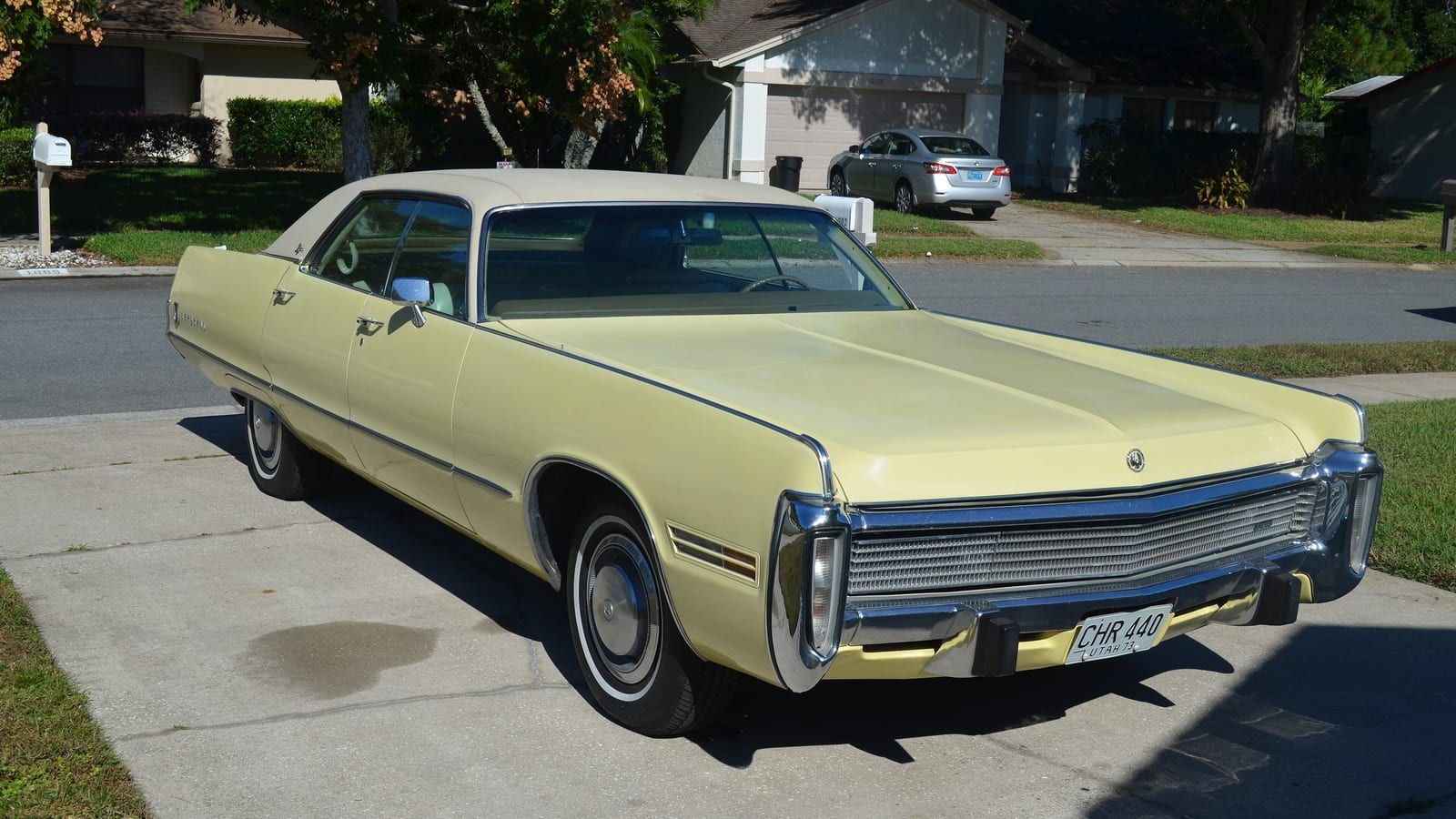 Pale yellow 1973 Imperial LeBaron coupe on a driveway, front three-quarter view.