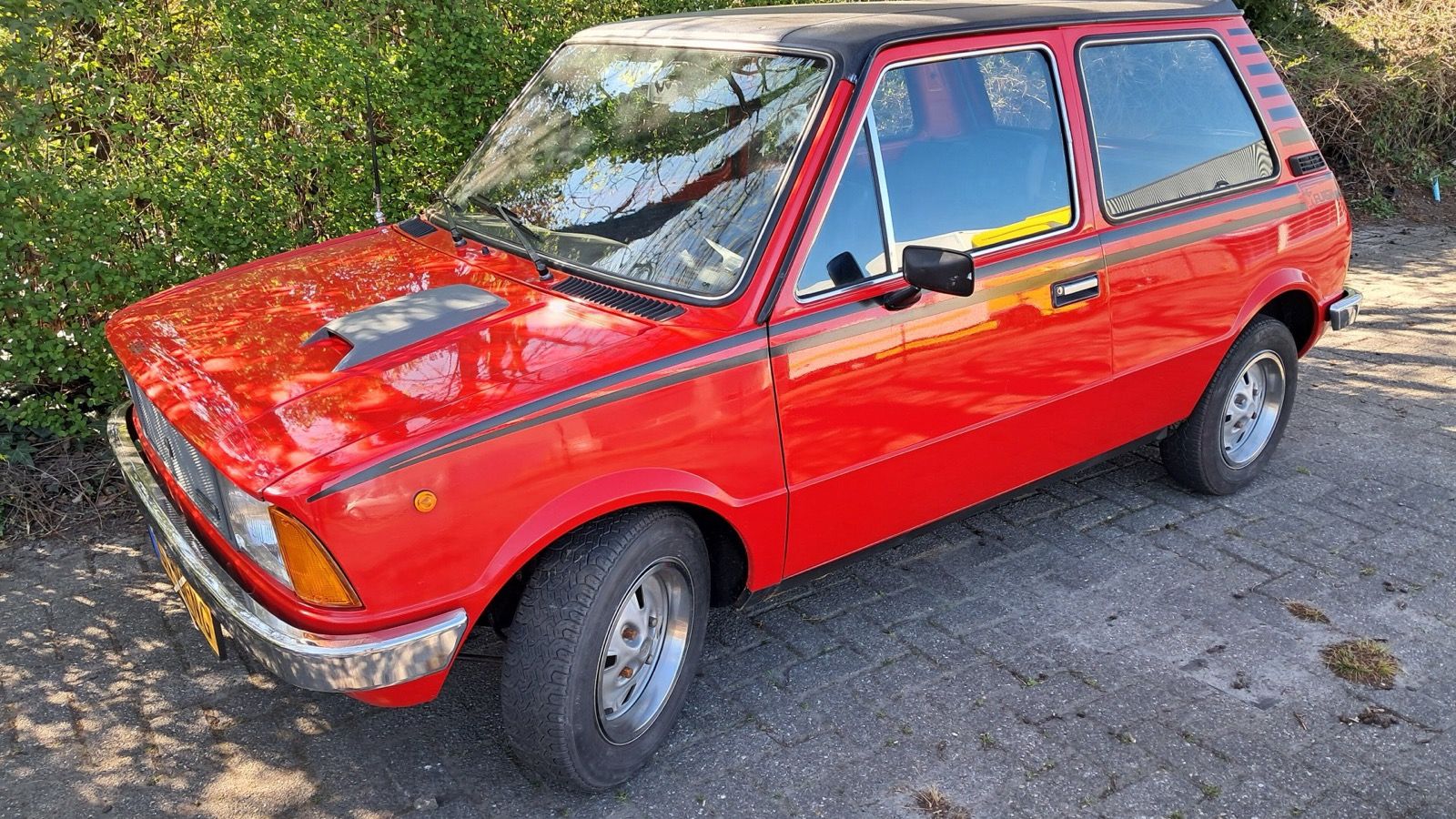 Red 1981 Innocenti Mini 90L 'Flash' with side stripes and vinyl roof, front three-quarter view