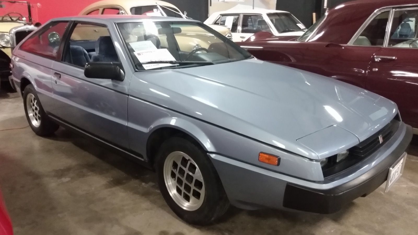 Light blue 1986 Isuzu Impulse coupe on museum display, front three-quarter view