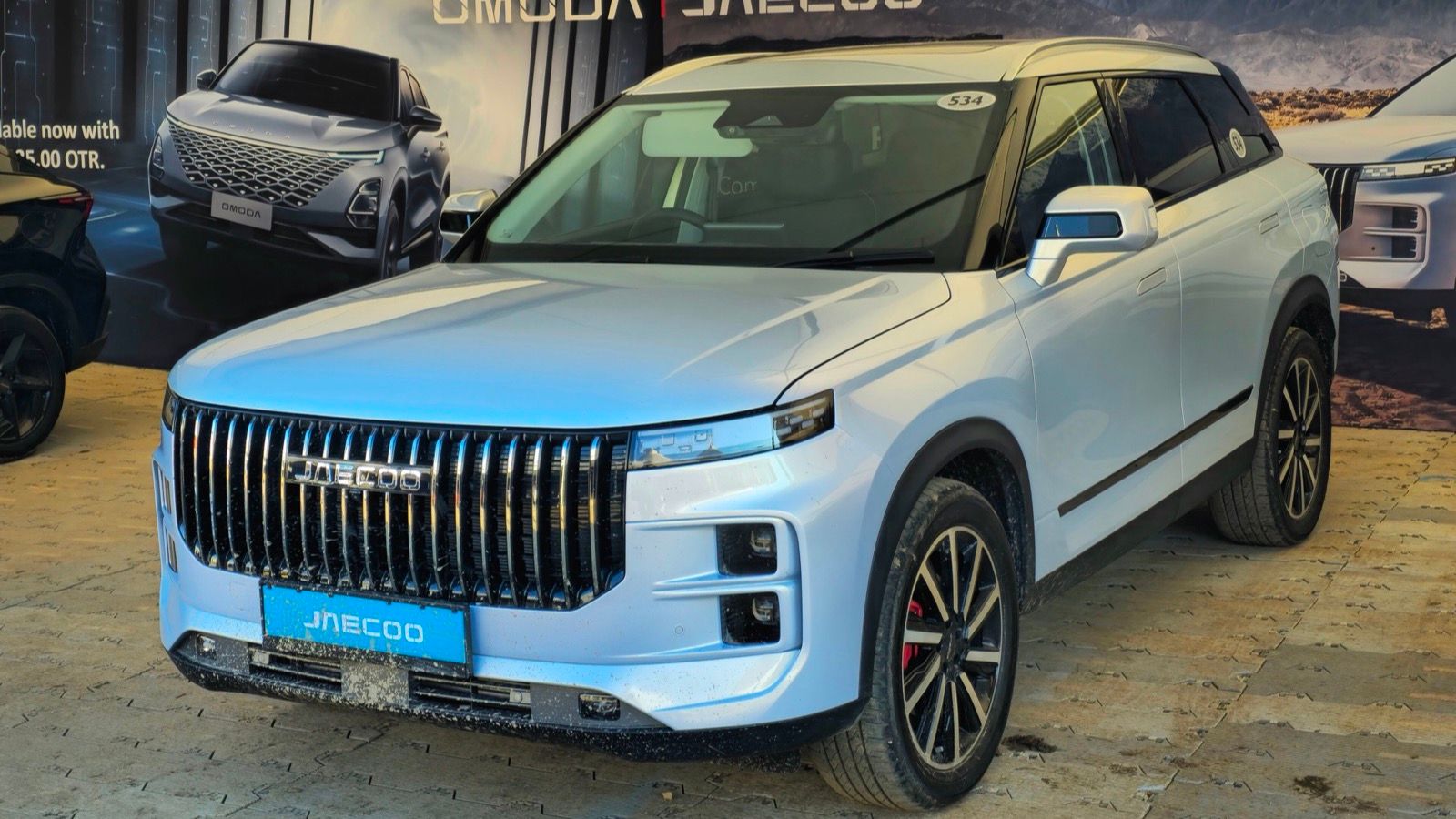 Pale blue 2024 Jaecoo J7 on a Jaecoo brand display stand, front three-quarter view