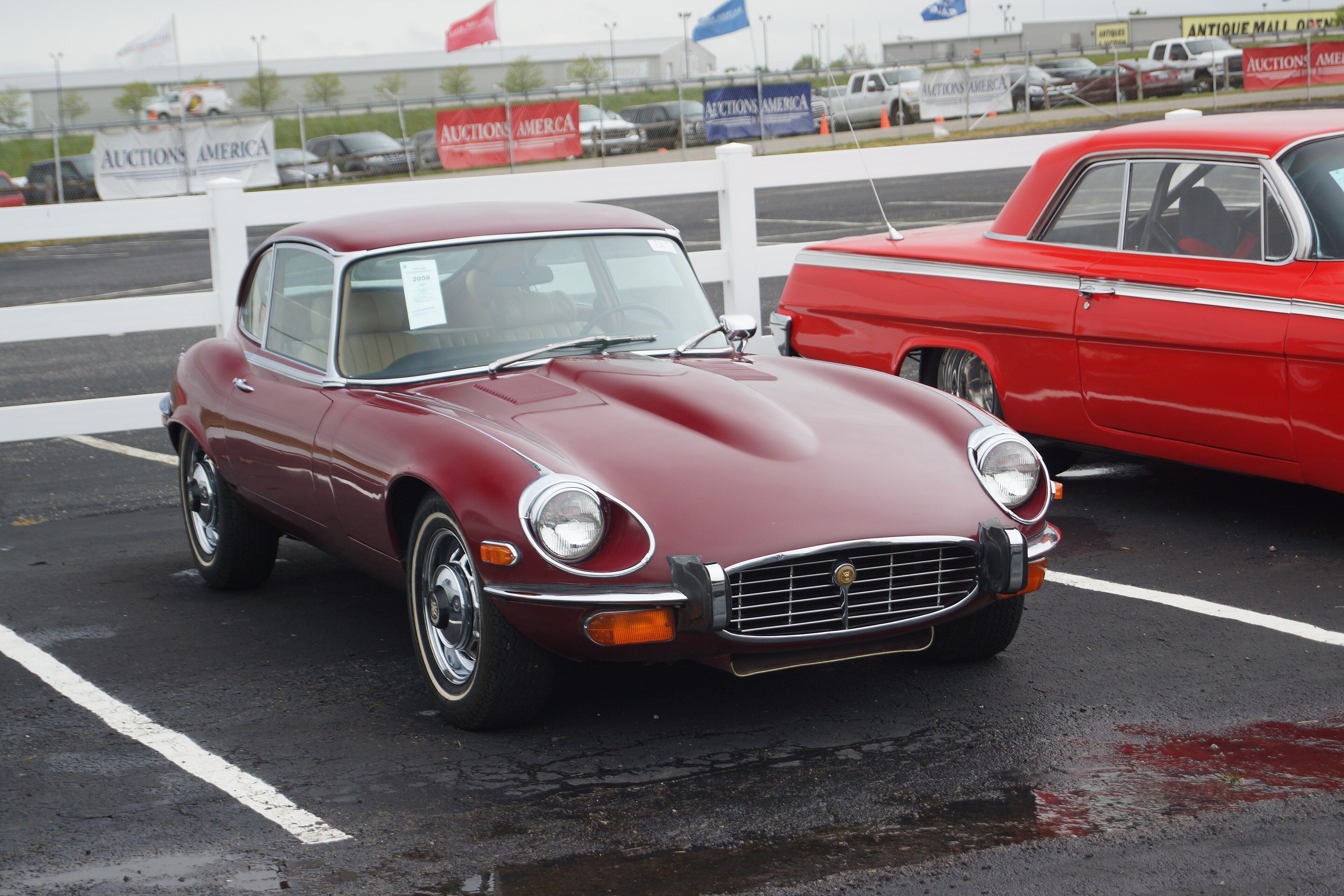 Maroon 1973 Jaguar E-Type Series 3 V12 2+2 coupe at an auction, front three-quarter view showing the cross-slat grille