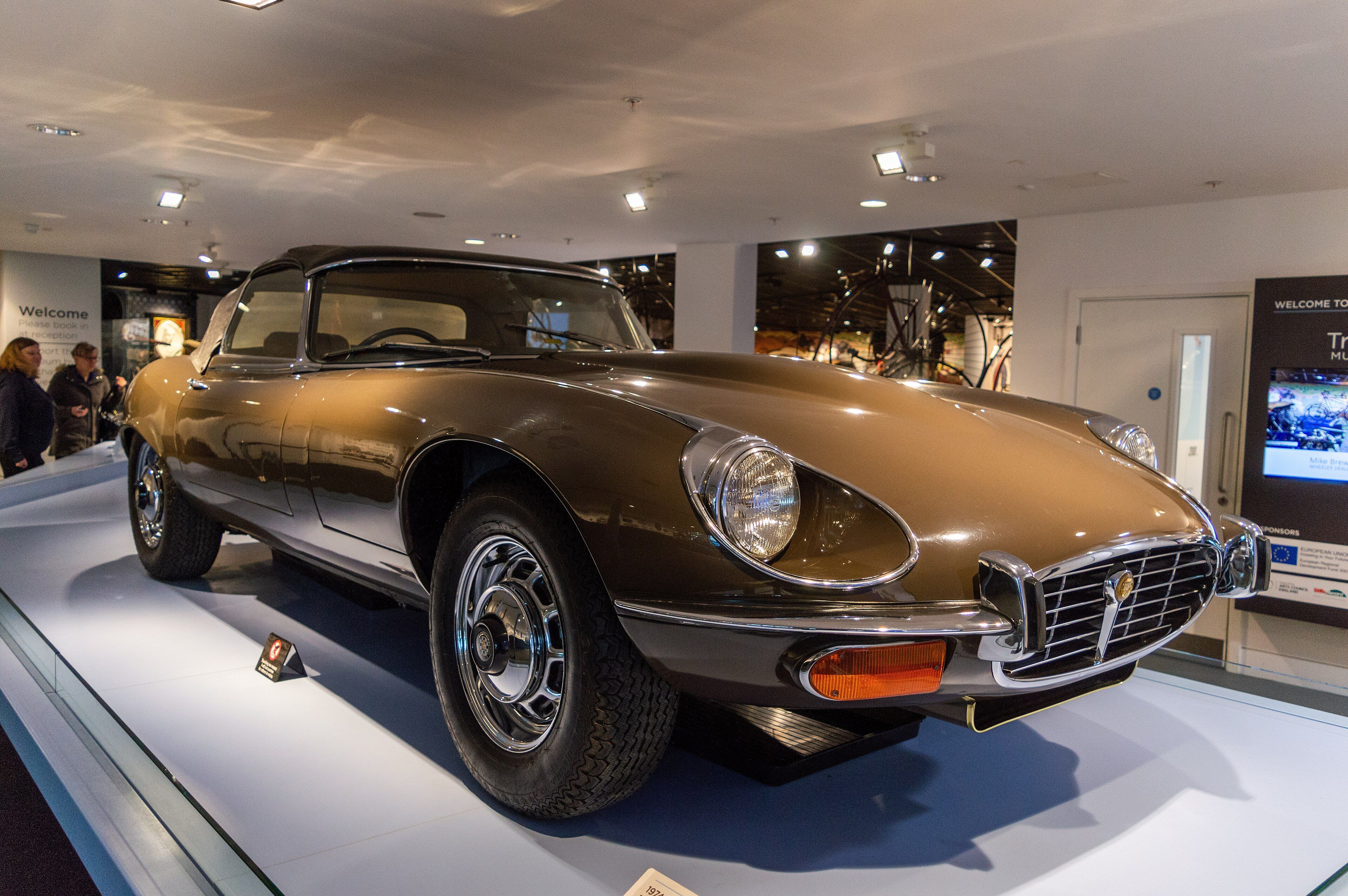 Bronze 1974 Jaguar E-Type Series 3 roadster on museum display, front three-quarter view