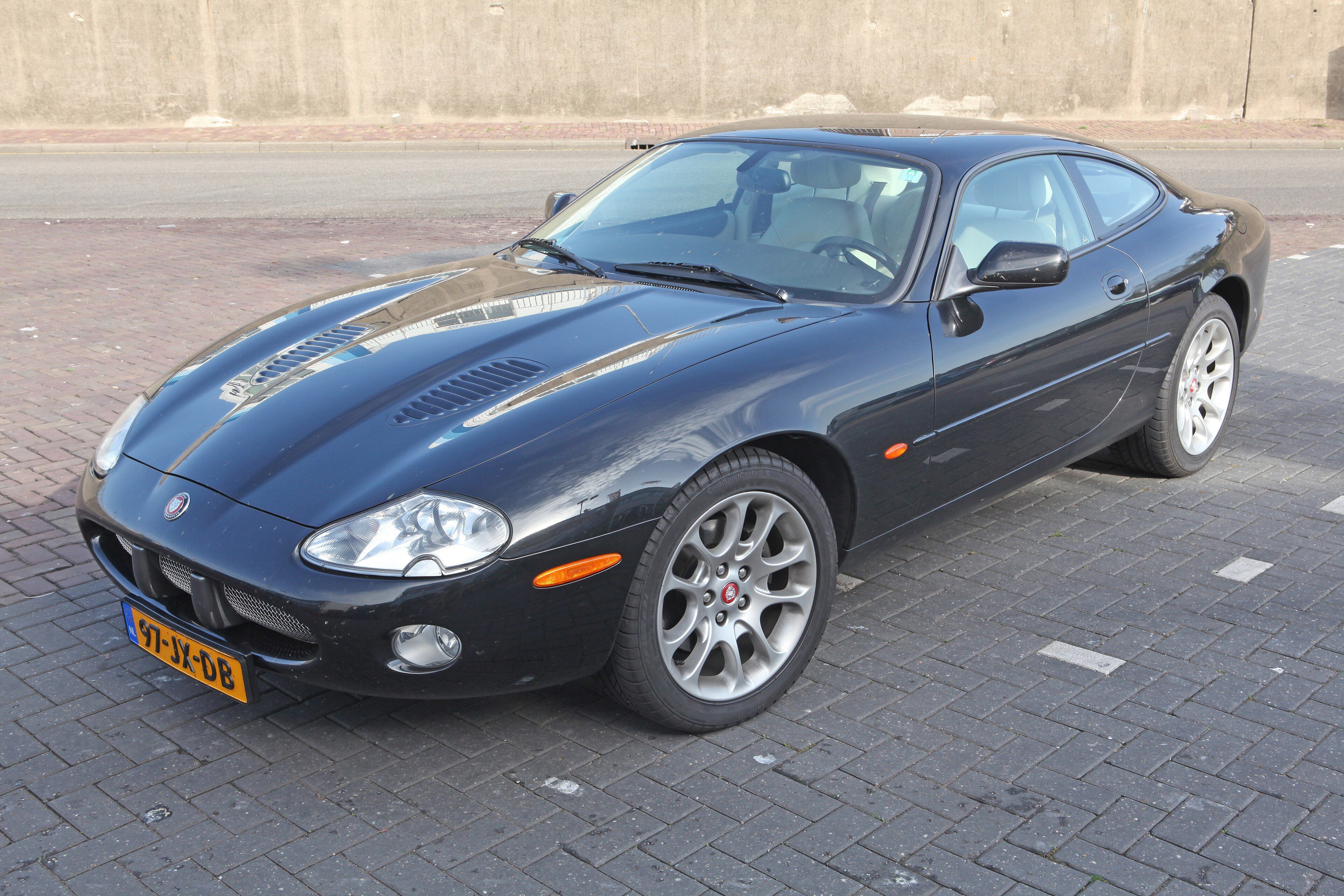 Black 2002 Jaguar XKR X100 coupe parked on brick paving, front three-quarter view