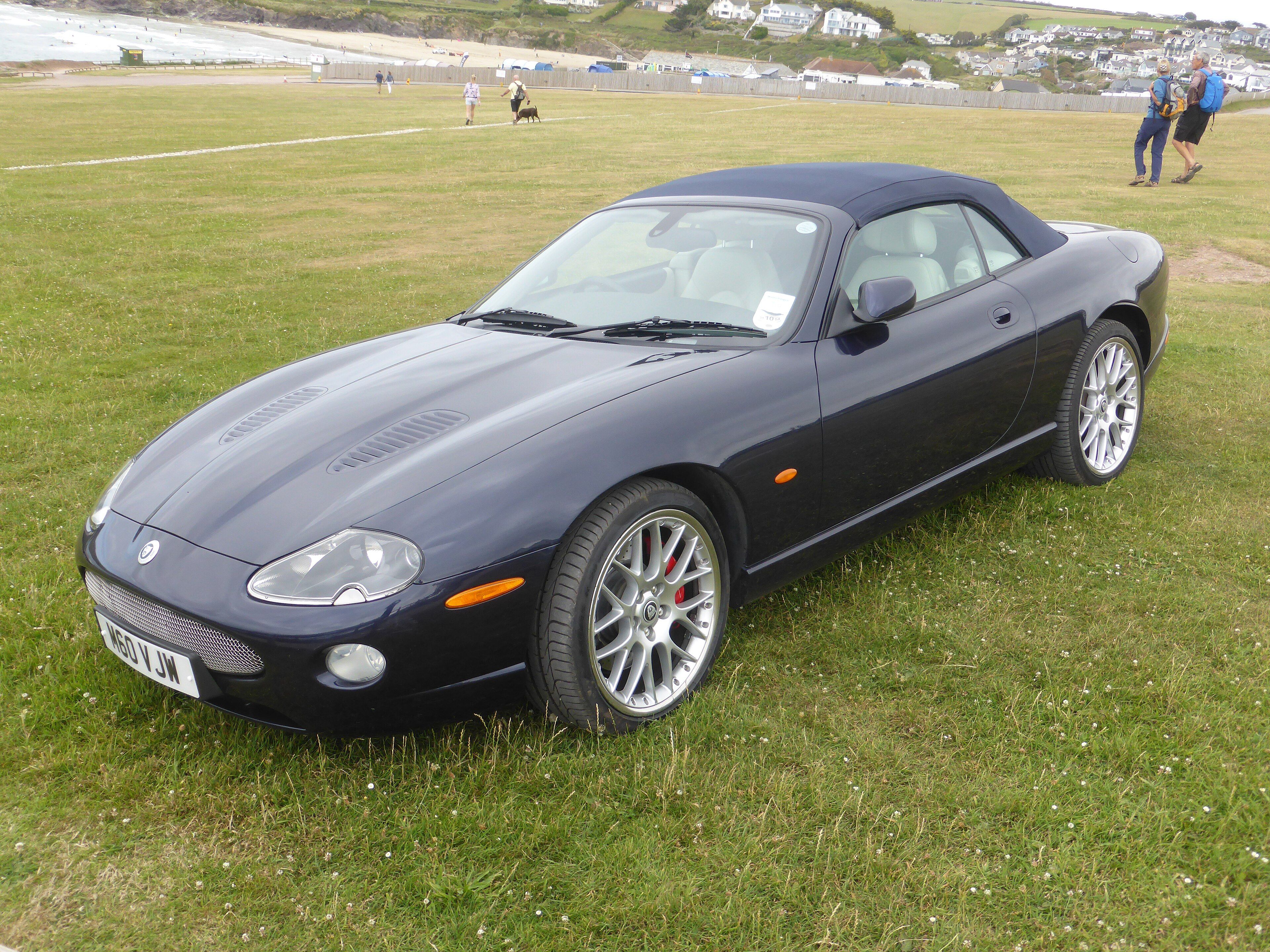Dark blue 2006 Jaguar XKR 4.2S X100 convertible on grass with the roof raised, front three-quarter view