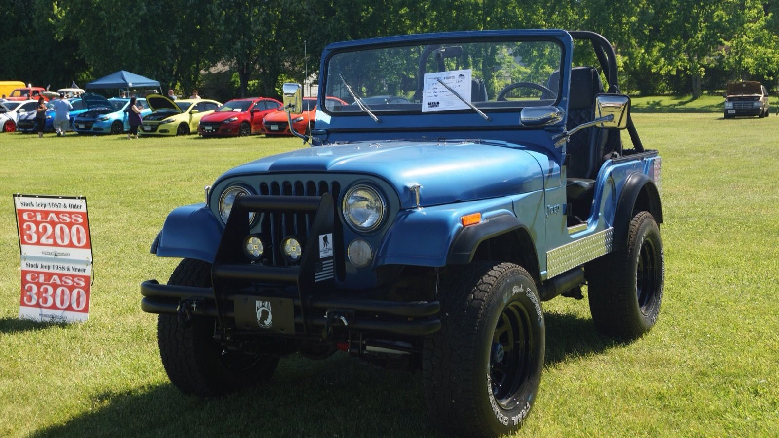 Blue 1974 Jeep CJ-5 open-top 4x4 on grass at a car show, front three-quarter view
