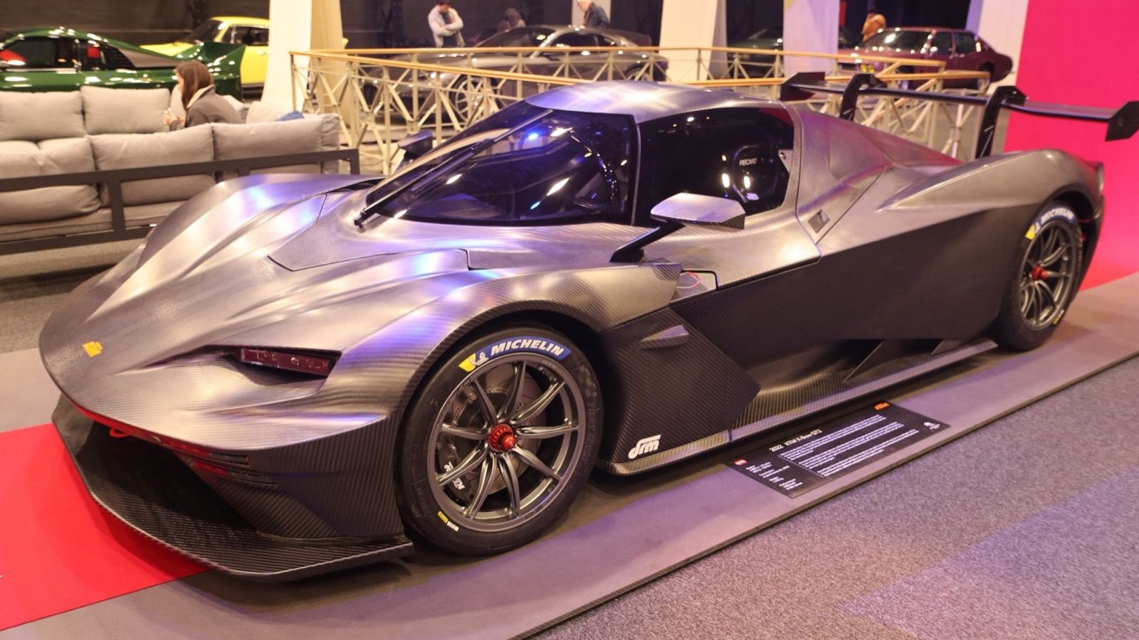 Bare-carbon KTM X-Bow GT2 on indoor display, front three-quarter view