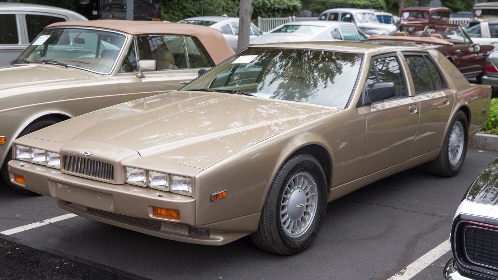 Sand-coloured Aston Martin Lagonda Series 4 saloon with fixed triple headlamps, front three-quarter view