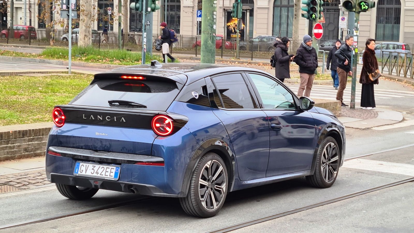 Blue 2024 Lancia Ypsilon electric hatchback on a city street, rear three-quarter view