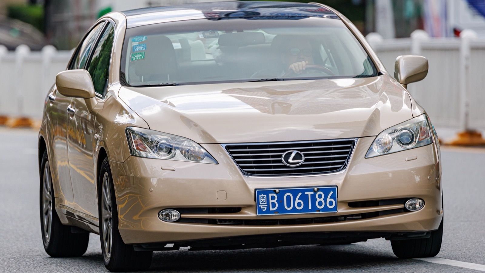 Gold fifth-generation Lexus ES 350 sedan on the road, front three-quarter view