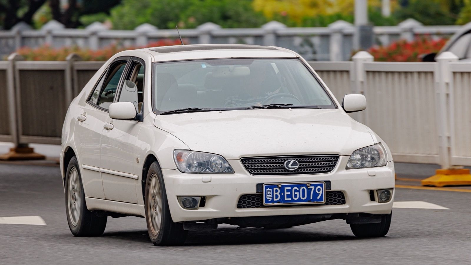 White first-generation Lexus IS sport sedan in traffic, front three-quarter view