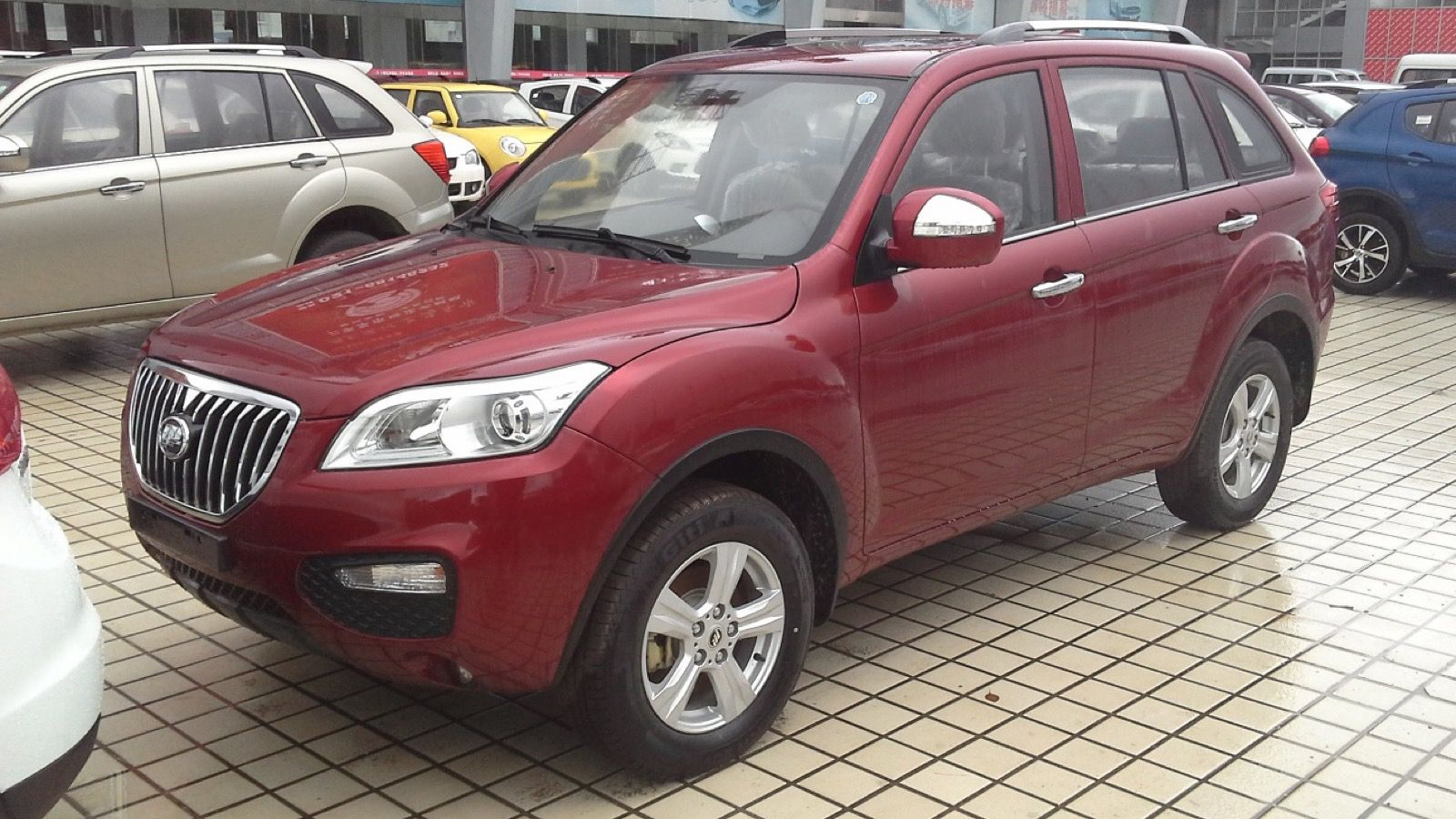 Red facelifted Lifan X60 crossover with vertical-slat grille, front three-quarter view