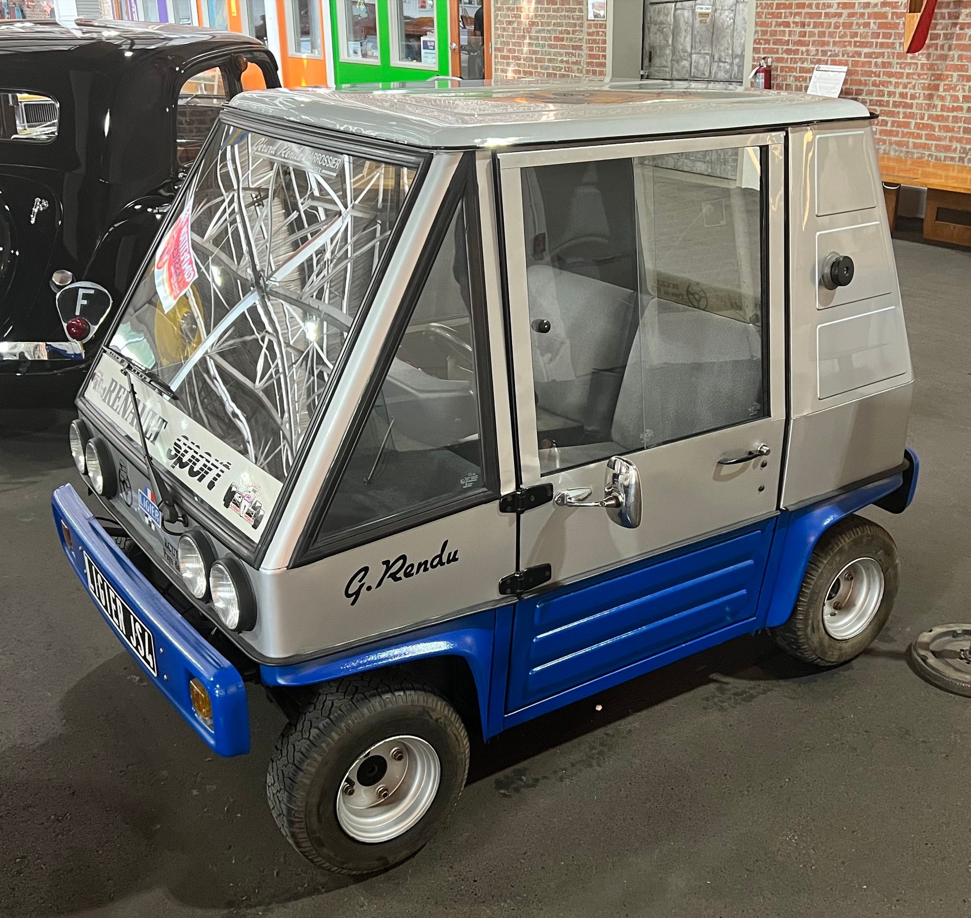 Silver and blue 1980 Ligier JS4 microcar on museum display, front three-quarter view