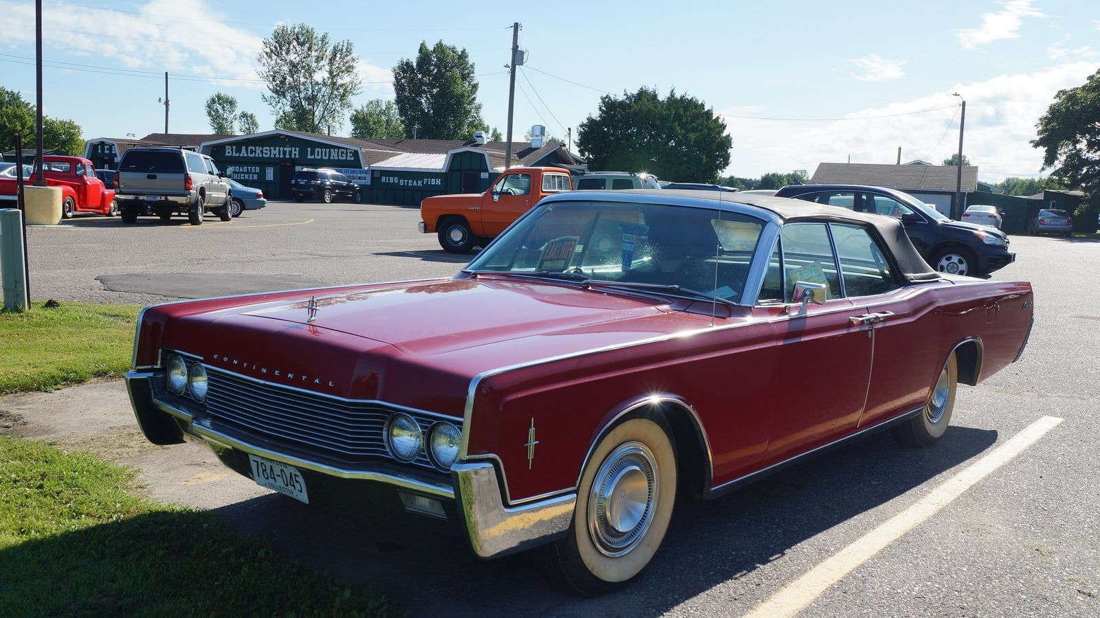 Dark red 1966 Lincoln Continental convertible, front three-quarter view in a parking lot