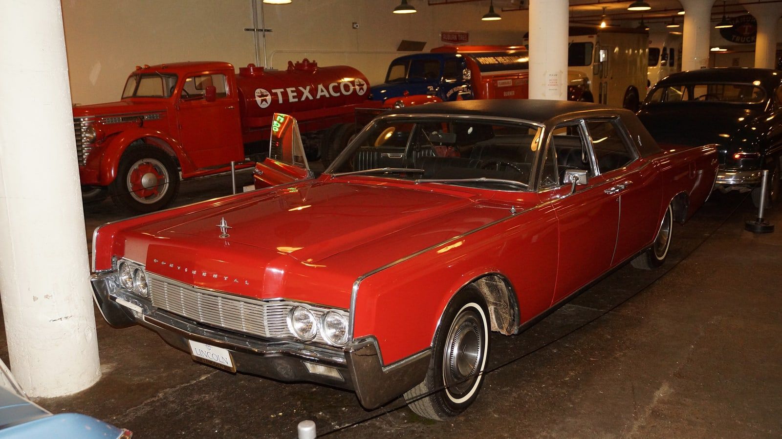 Red 1967 Lincoln Continental sedan, front three-quarter view inside a museum
