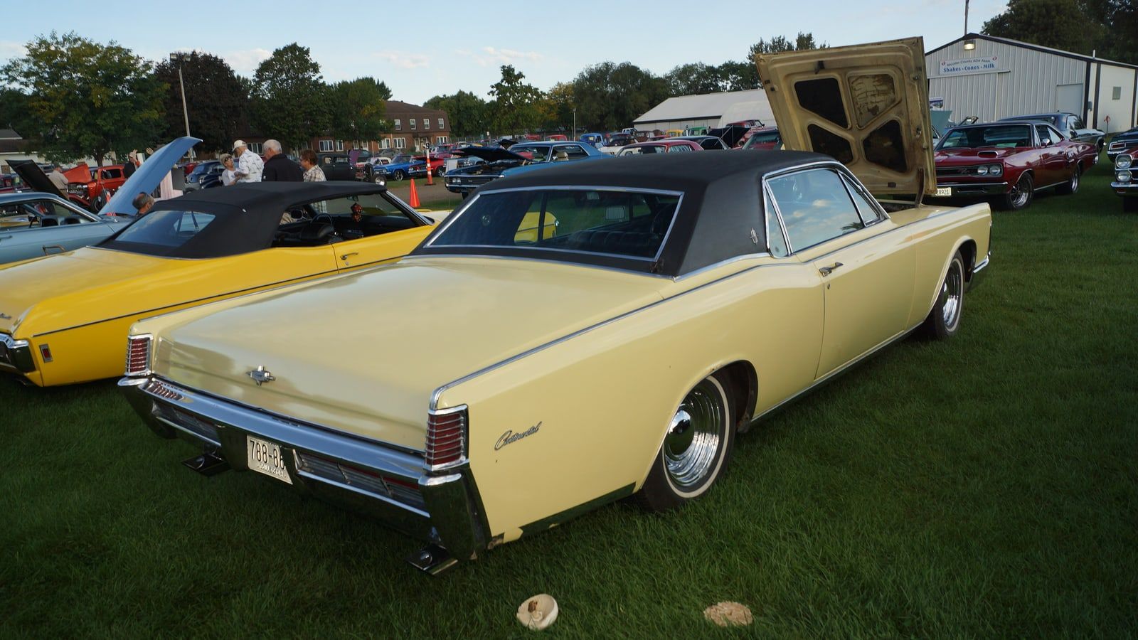 Pale yellow 1968 Lincoln Continental convertible, rear three-quarter view on grass at a car show
