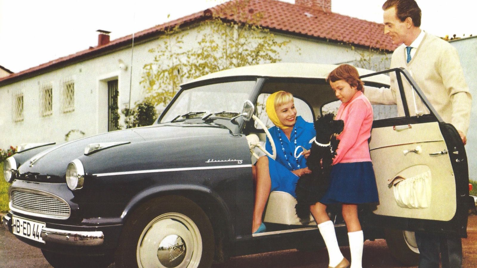 Dark blue 1959 Lloyd Alexander TS with cream roof photographed outside a house, side profile
