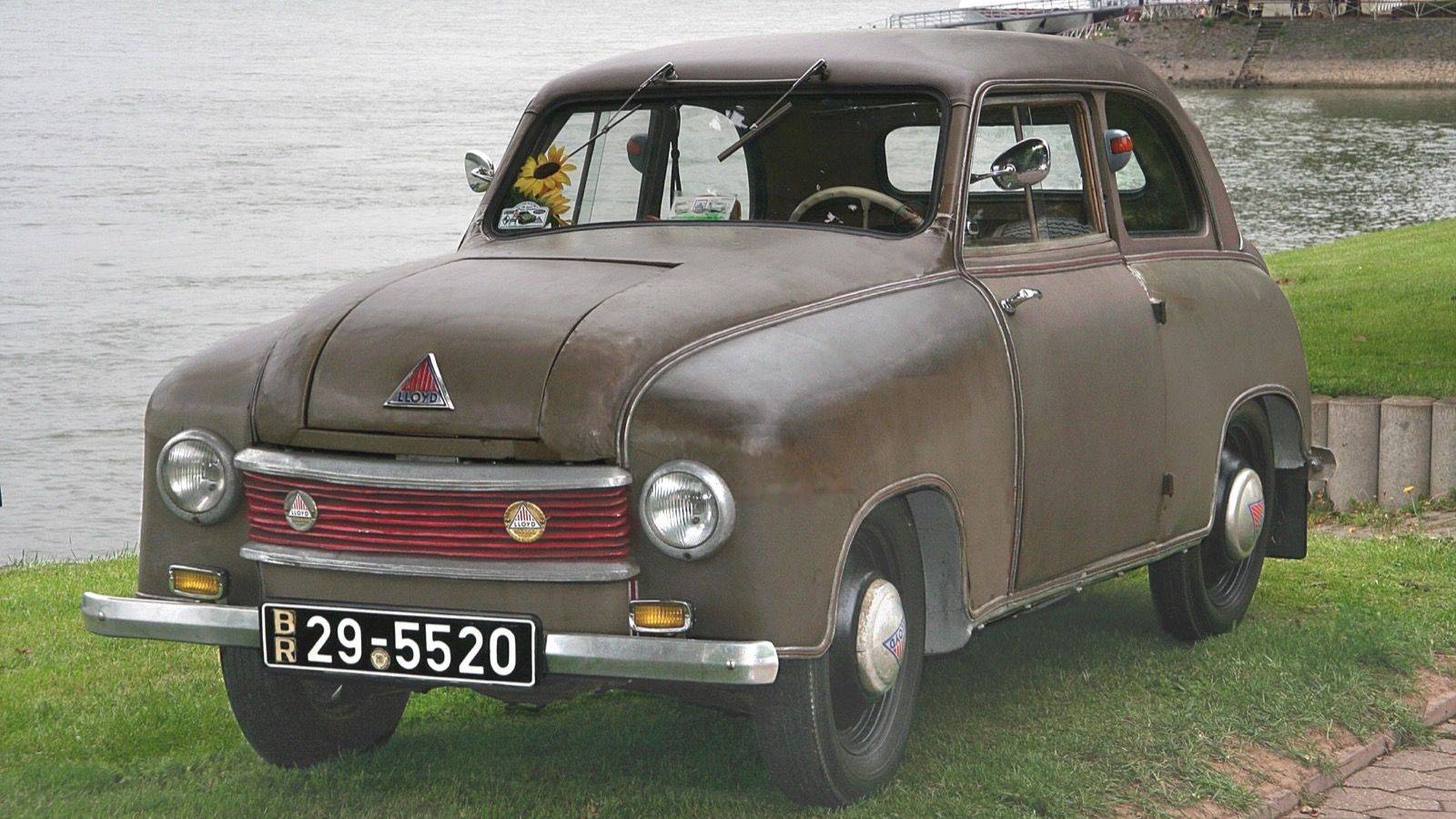 Brown fabric-bodied Lloyd LP 300 of the 1950–51 model years parked by a river, front three-quarter view