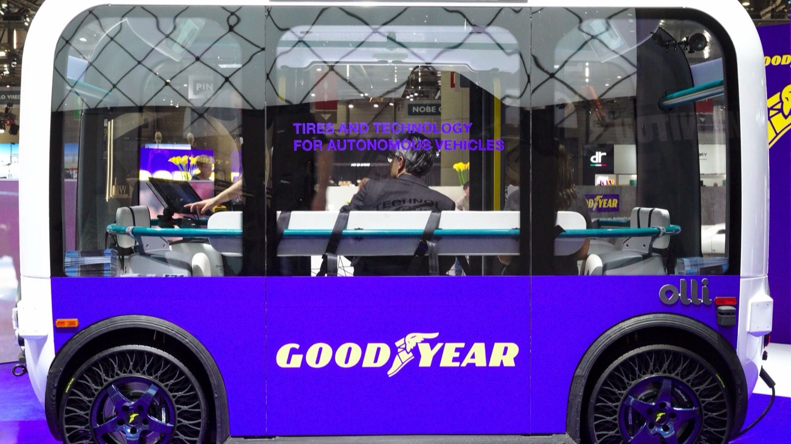 Purple and white Local Motors Olli 2.0 autonomous electric shuttle in side profile, wearing Goodyear airless tyres