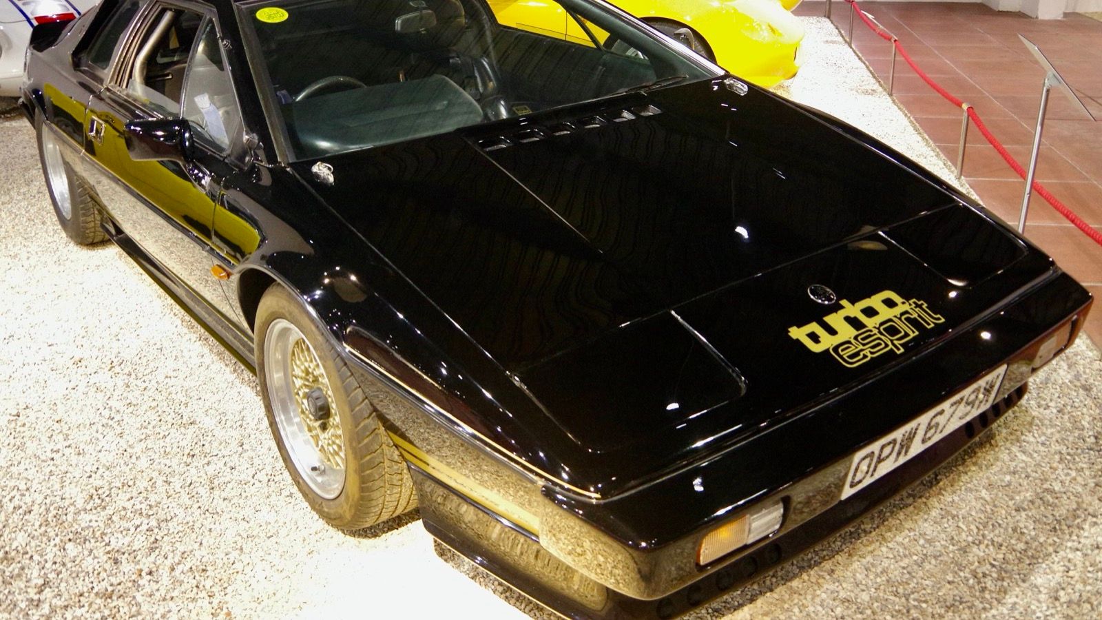 Black and gold 1981 Lotus Turbo Esprit on museum display, front three-quarter view.