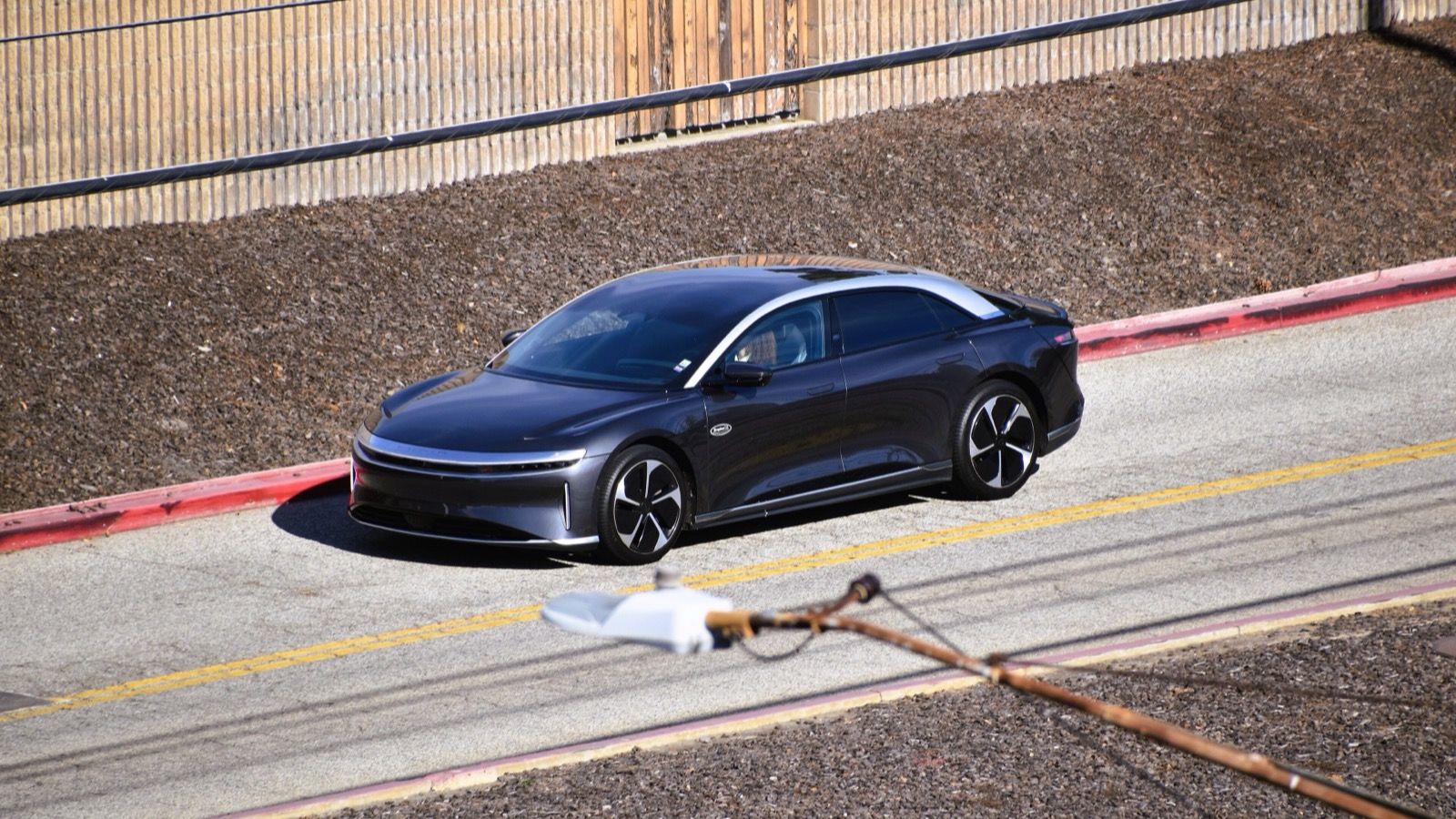 Dark grey 2022 Lucid Air sedan parked at a kerb, elevated front three-quarter view