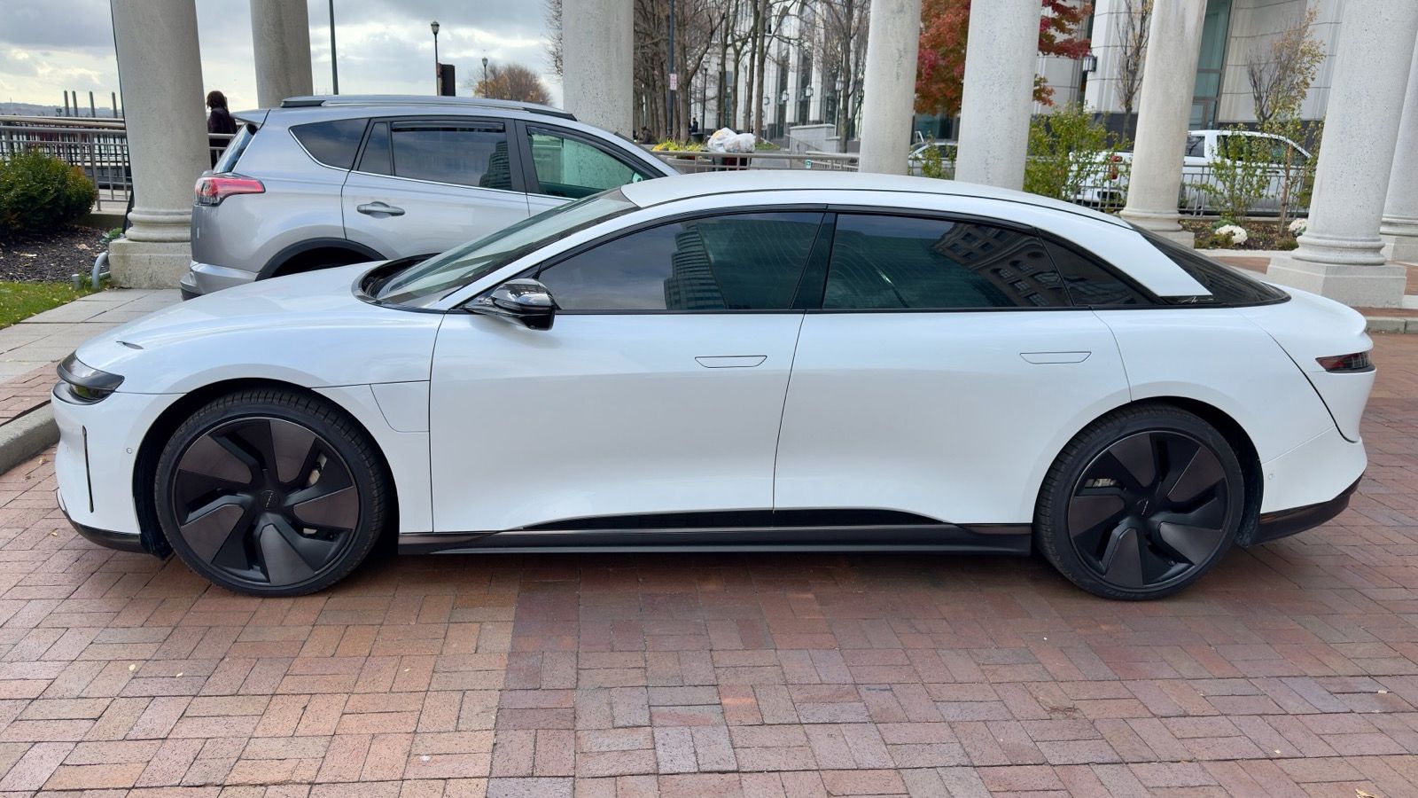 White 2023 Lucid Air sedan on a brick forecourt, side profile