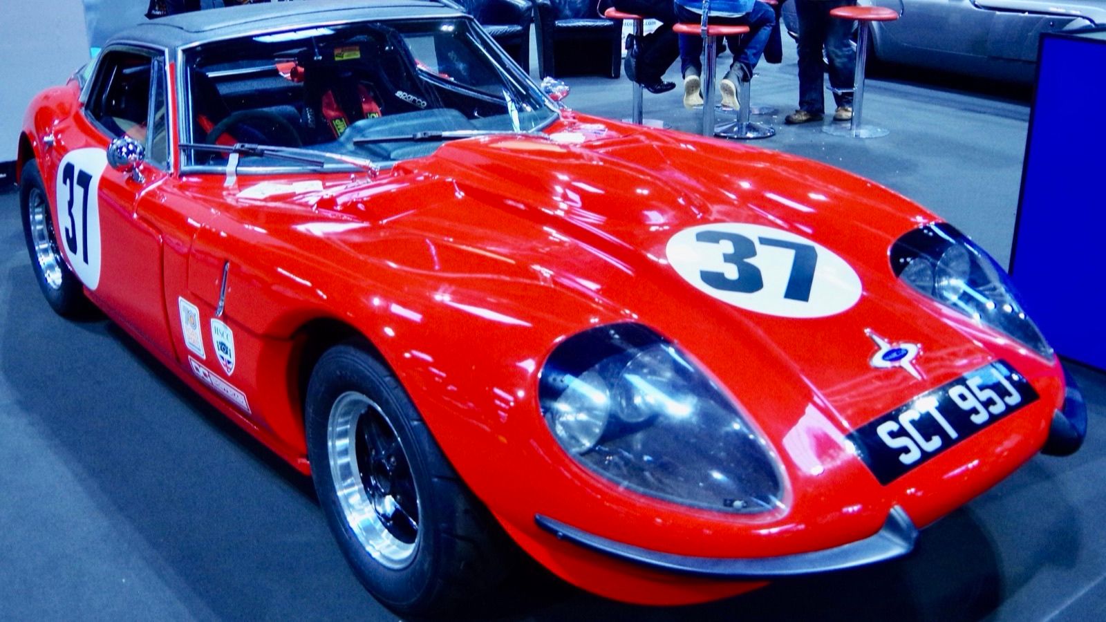 Red 1970 Marcos GT competition coupe with racing roundels, front three-quarter view