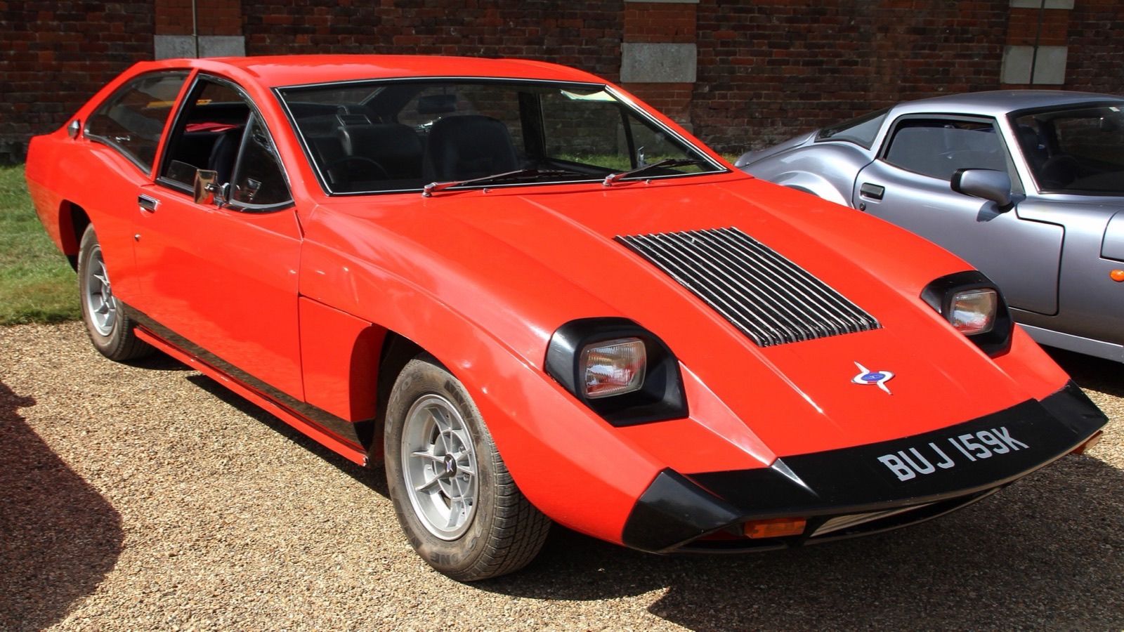 Red 1971 Marcos Mantis M70 four-seat coupe, front three-quarter view
