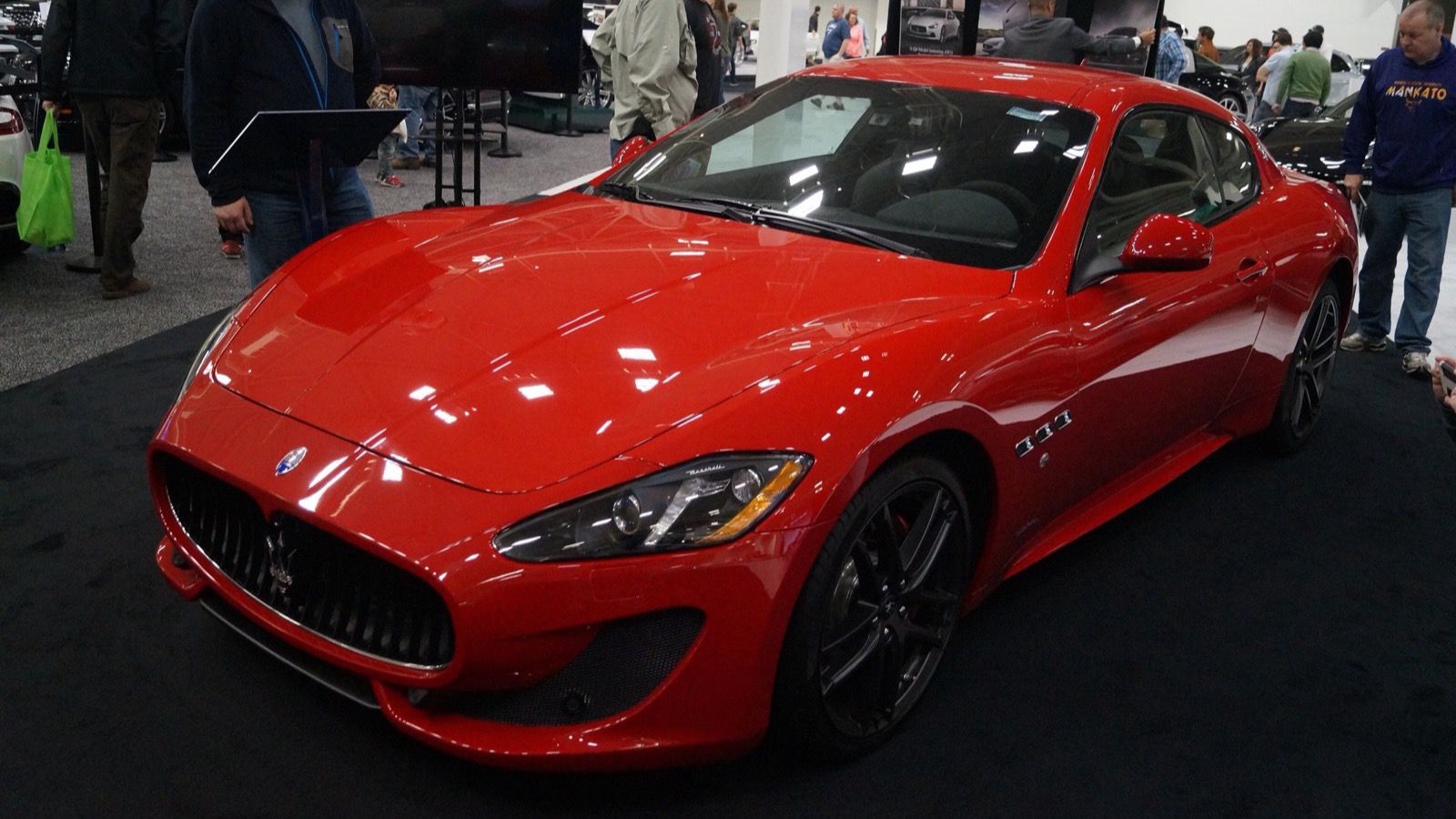 Red 2016 Maserati GranTurismo Sport coupe on an auto-show stand, front three-quarter view