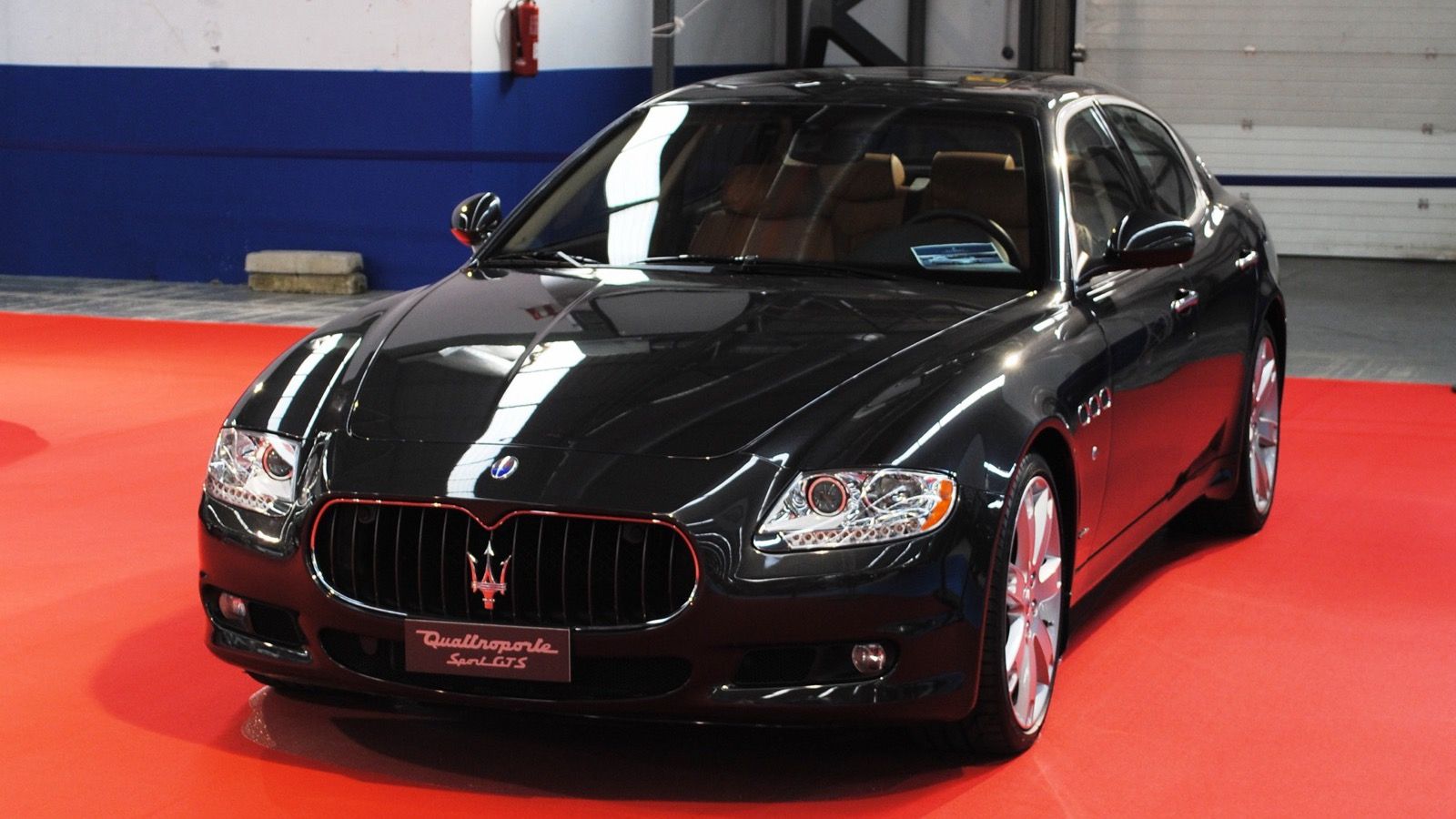 Black 2012 Maserati Quattroporte Sport GT S sedan on a show stand, front three-quarter view