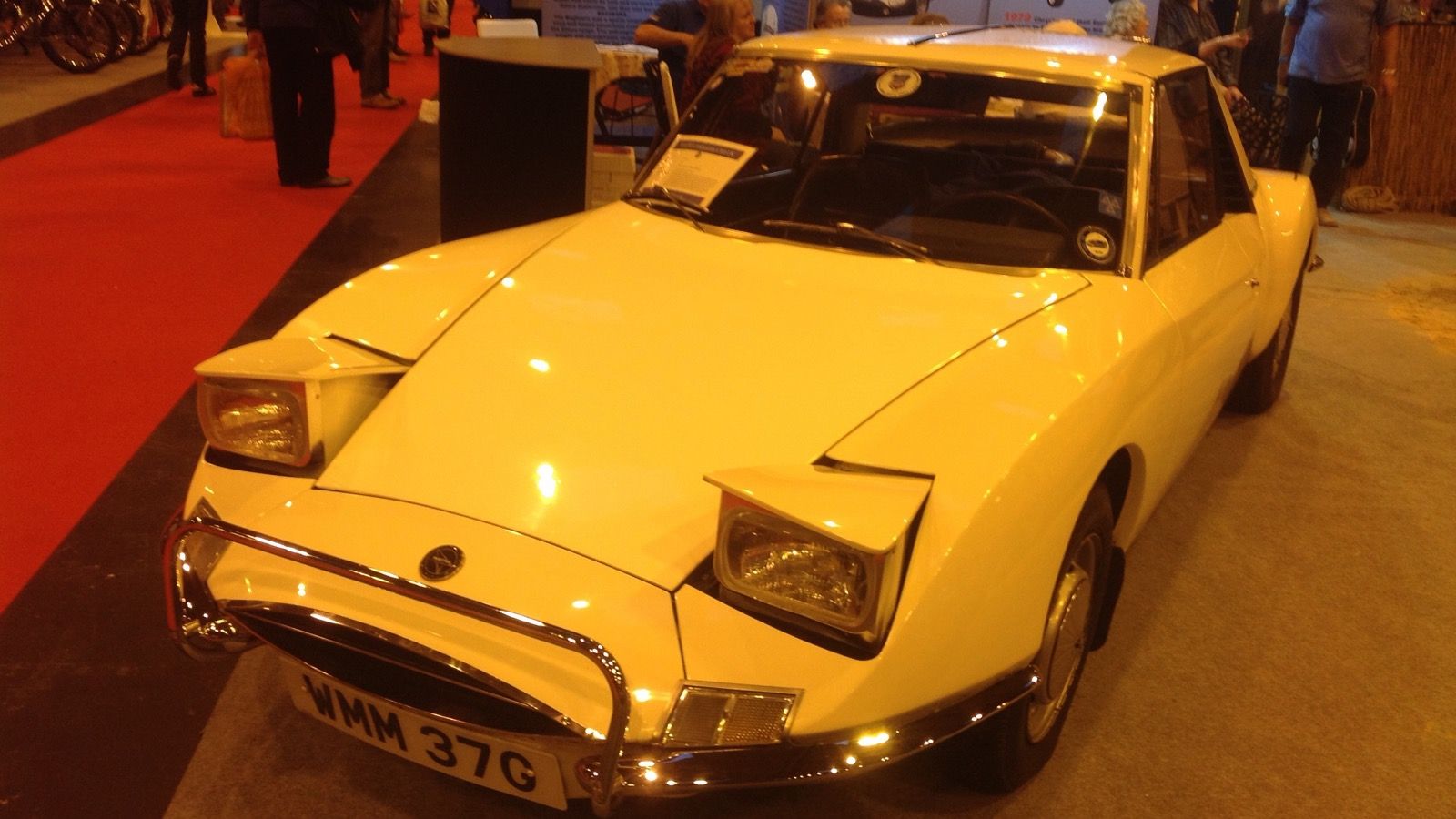 Cream 1969 Matra M530 with pop-up headlamps raised at an indoor classic car show, front three-quarter view