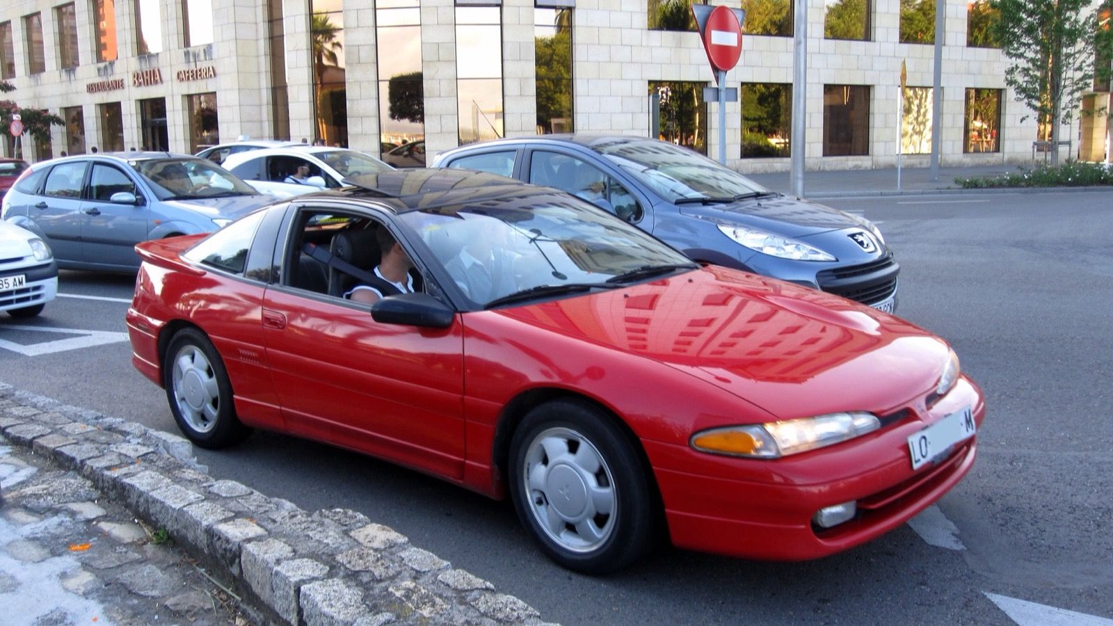 Red 1993 Mitsubishi Eclipse GSX coupe parked on a street, front three-quarter view
