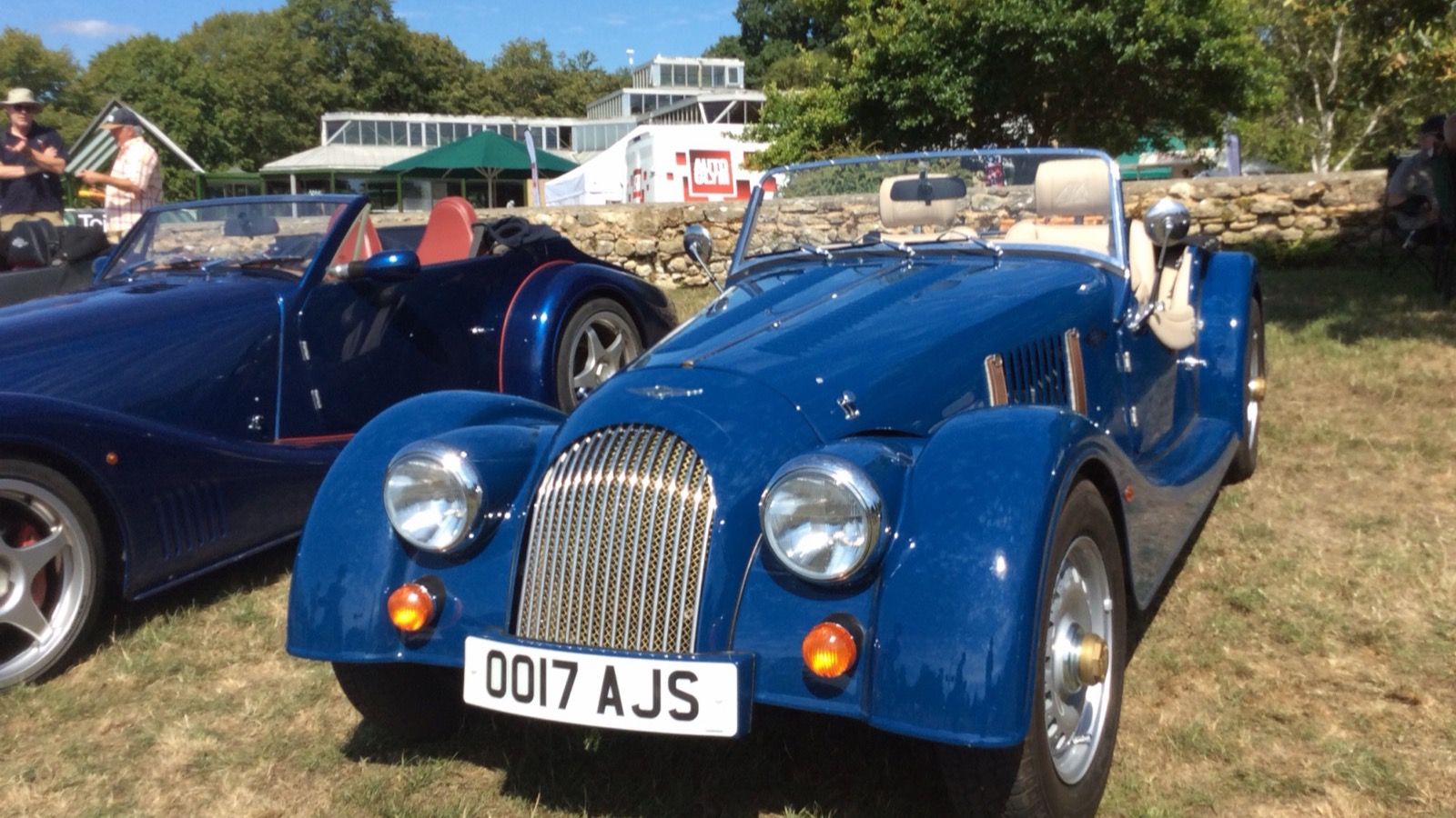 Blue 2017 Morgan 4/4 roadster on grass, front three-quarter view