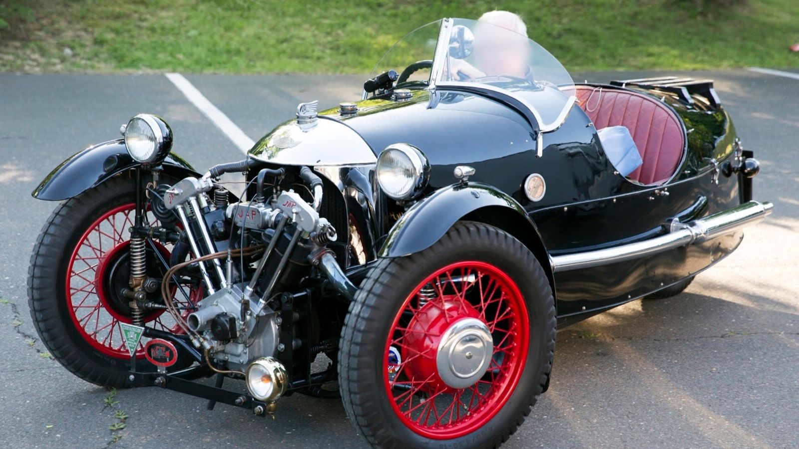 Black 1934 Morgan Super Sports three-wheeler with red wire wheels and exposed JAP V-twin, front three-quarter view