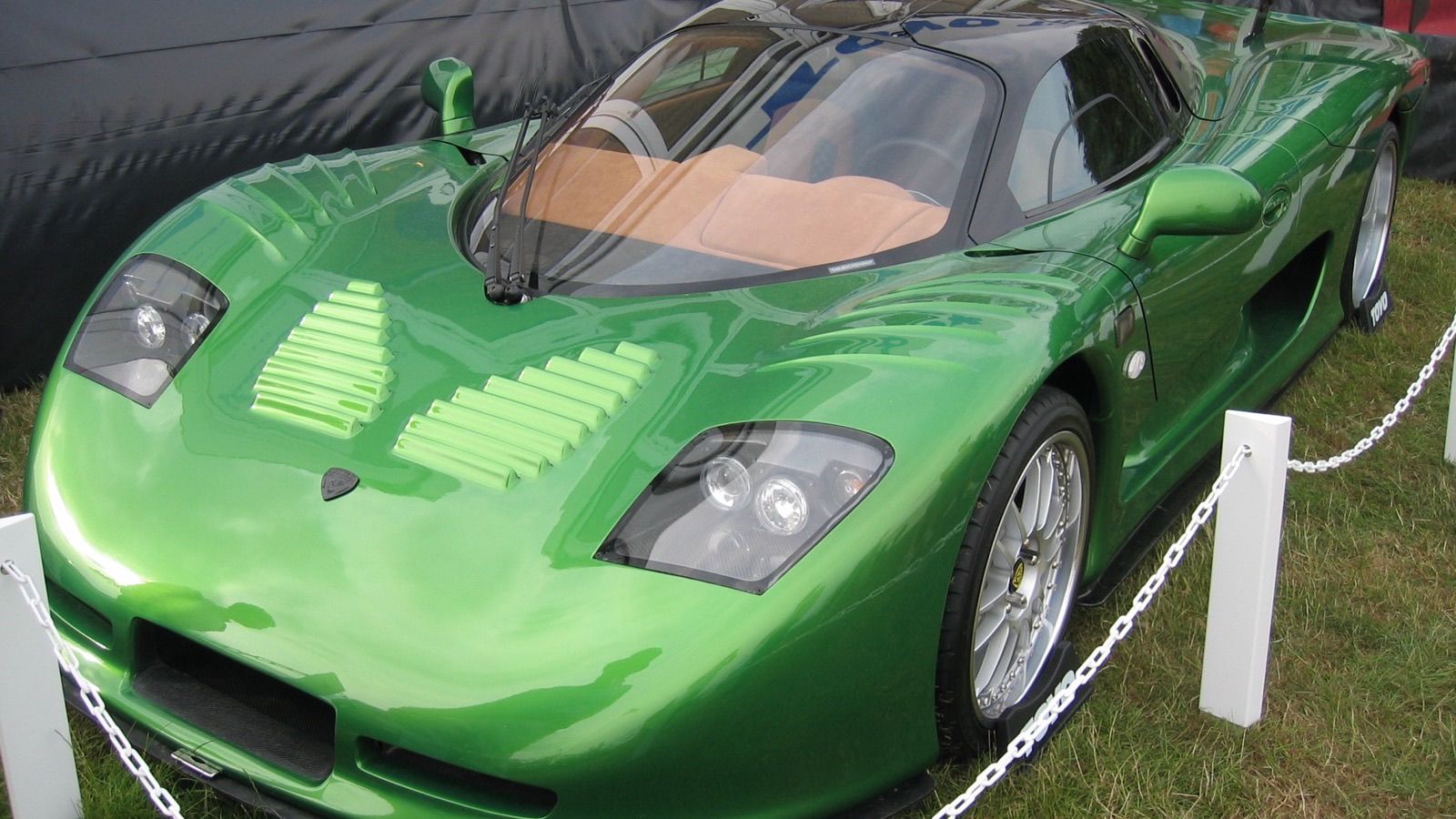 Green Mosler MT900 with rear wing on grass at the 2006 Goodwood Festival of Speed, front three-quarter view
