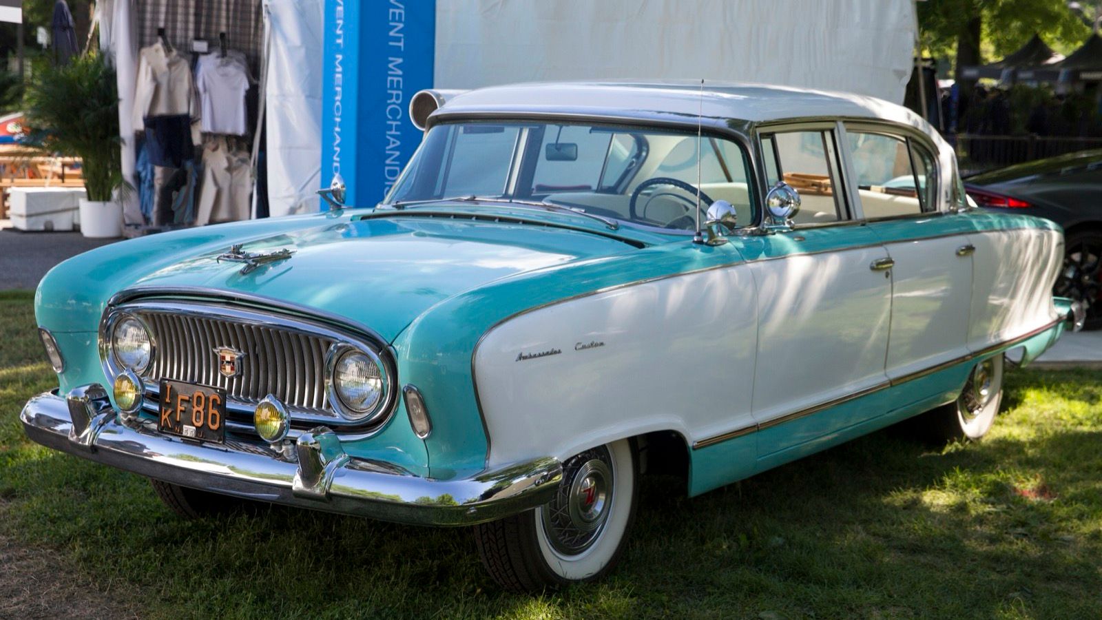 Turquoise and white 1955 Nash Ambassador Custom four-door sedan, front three-quarter view on grass