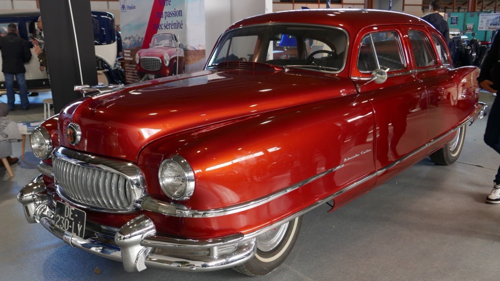 Red Nash Ambassador Custom four-door sedan of the Airflyte era, front three-quarter view at an indoor classic car show