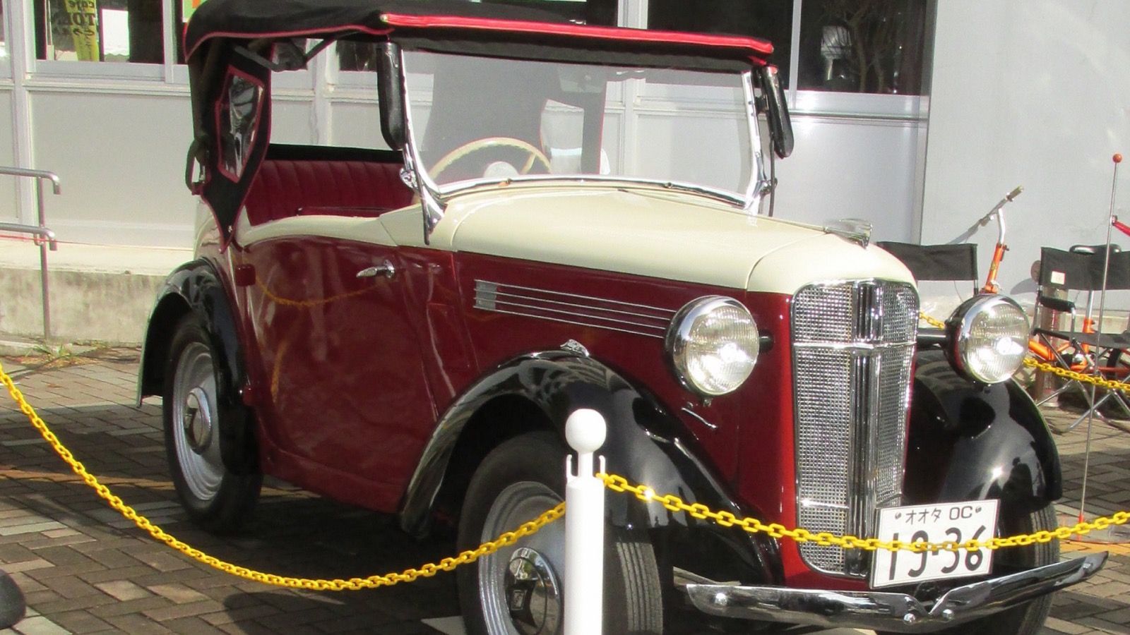 Maroon and cream 1936 Ohta Type OC phaeton with the folding top down, front three-quarter view