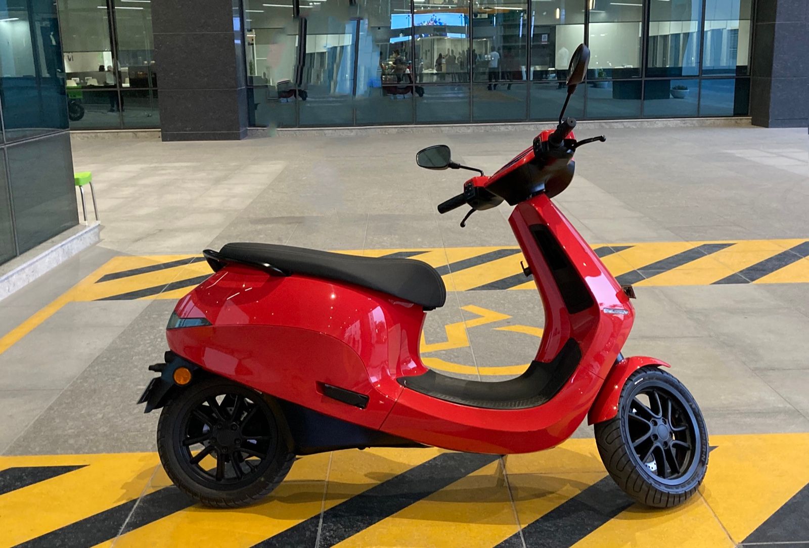 Red Ola S1 Pro Gen 1 electric scooter parked outside an office building, side profile