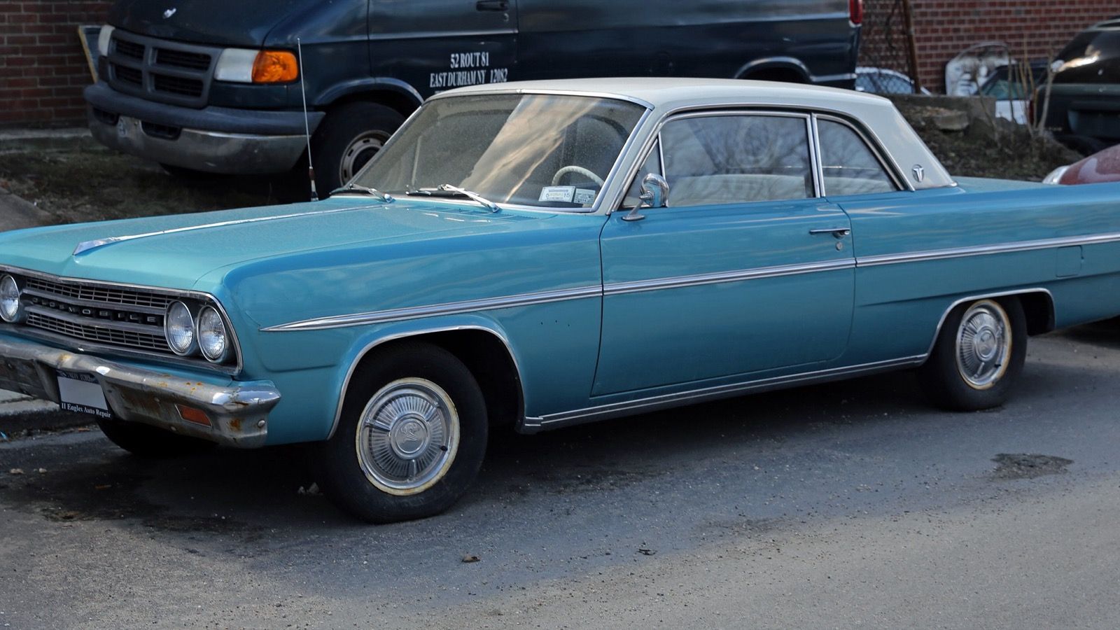 Turquoise 1963 Oldsmobile F-85 Cutlass two-door coupe with white roof, front three-quarter view