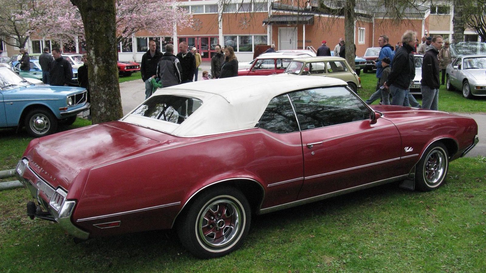 Maroon A-body Oldsmobile Cutlass convertible with white top, side view