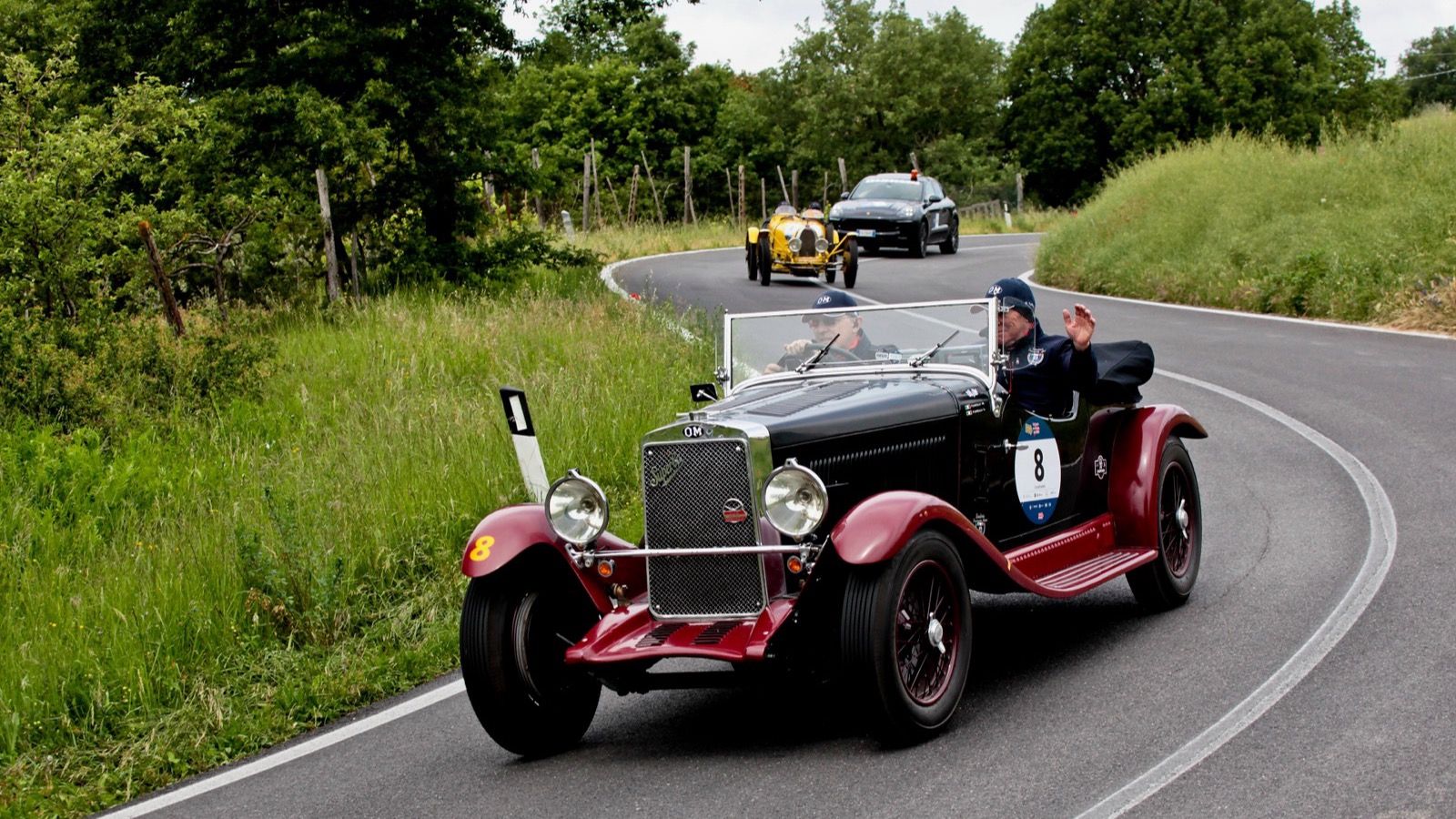 Dark red 1929 OM 665 S TT Superba open sports car cornering on a rally road, front three-quarter view