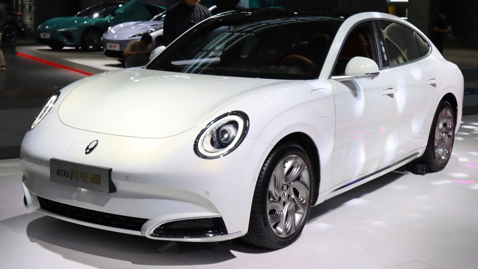 White Ora Lightning Cat electric fastback on a show stand, front three-quarter view