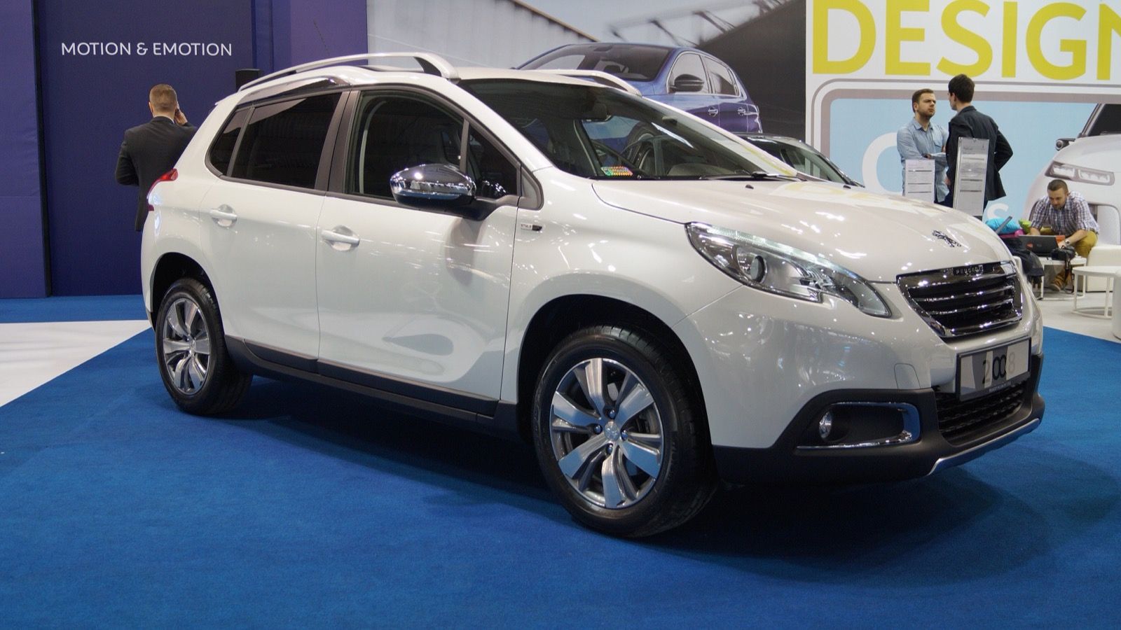 White first-generation Peugeot 2008 crossover on a motor-show stand, front three-quarter view