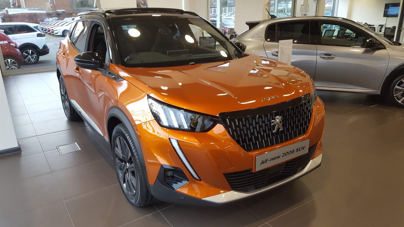 Orange 2020 Peugeot 2008 GT crossover in a dealership, front three-quarter view