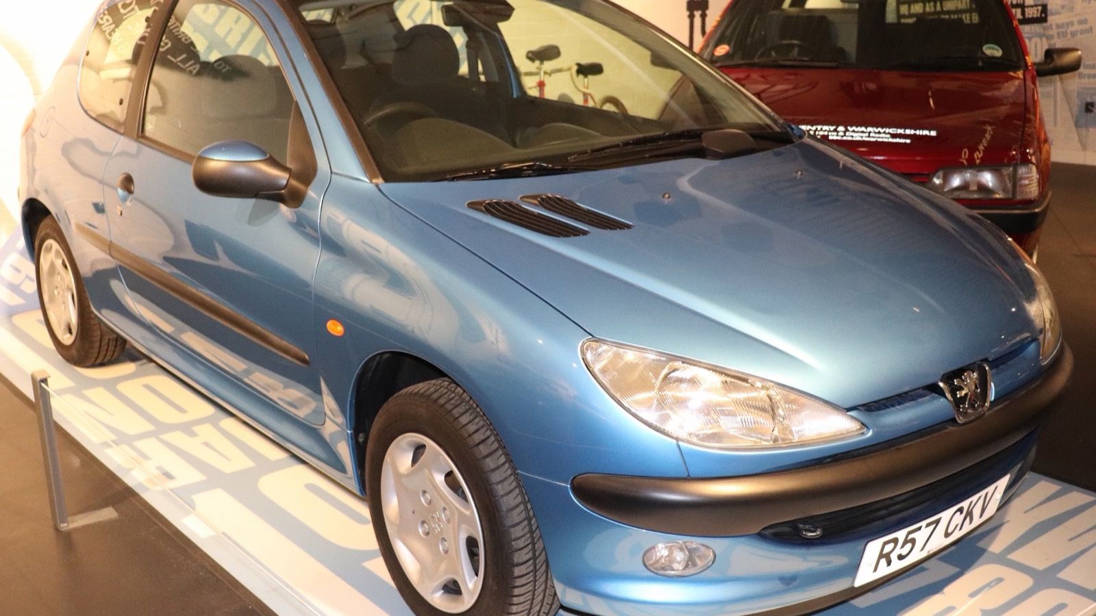 Blue Peugeot 206 three-door hatchback on museum display, front three-quarter view