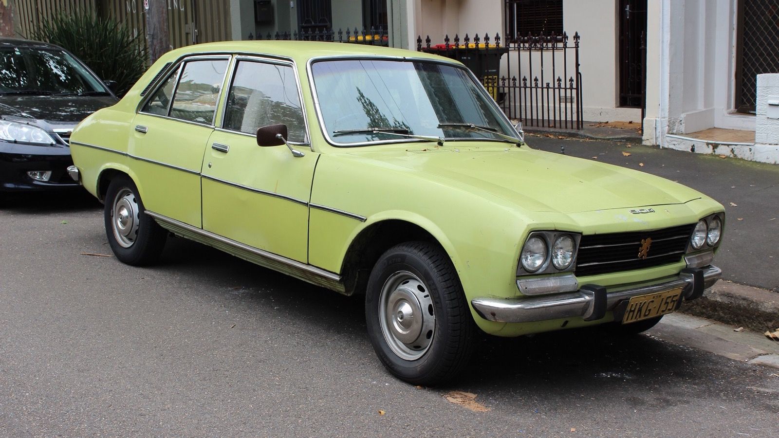 Lime green 1975 Peugeot 504 saloon parked at a kerb, front three-quarter view