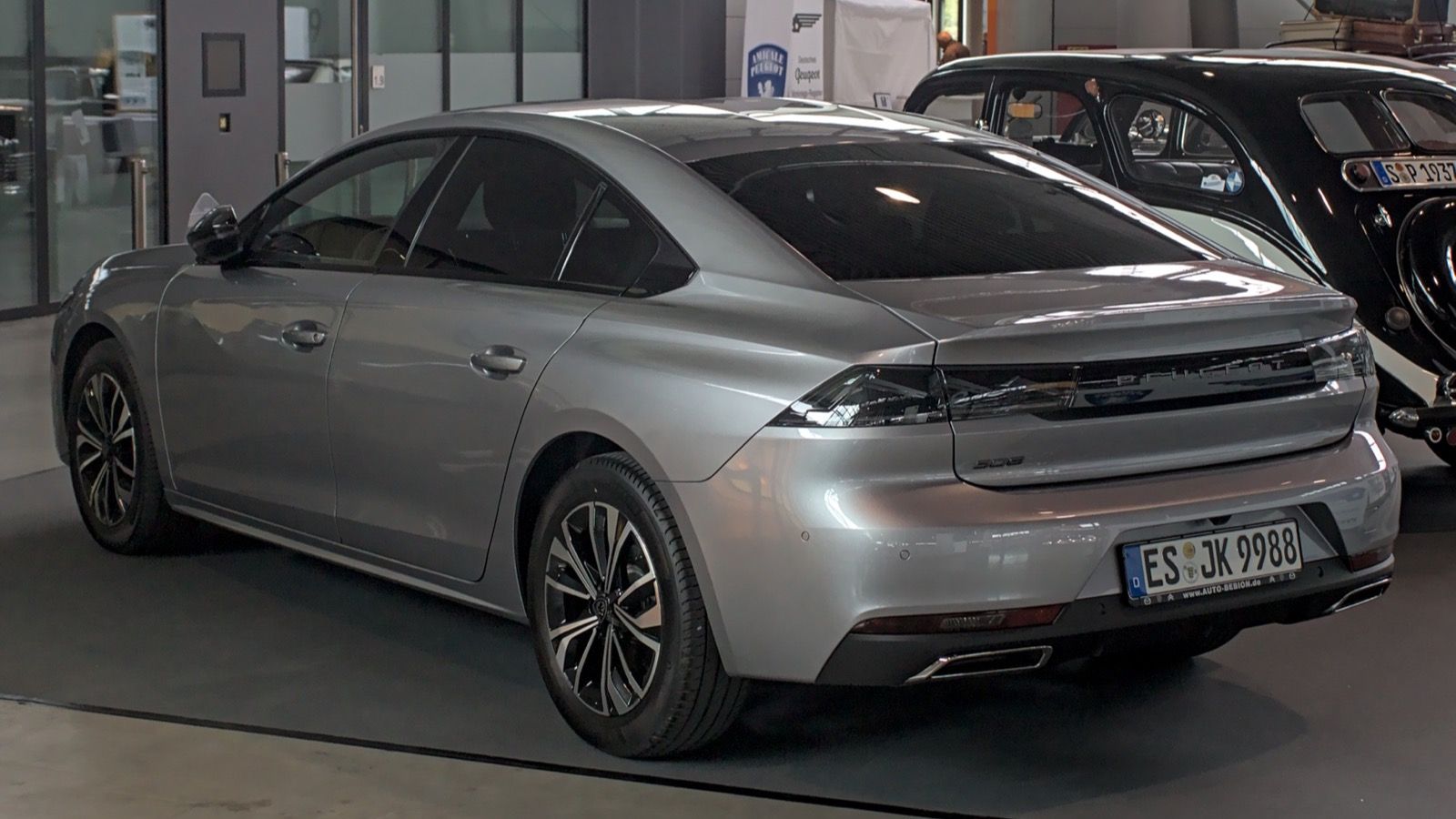 Silver 2023 Peugeot 508 fastback on indoor display, rear three-quarter view