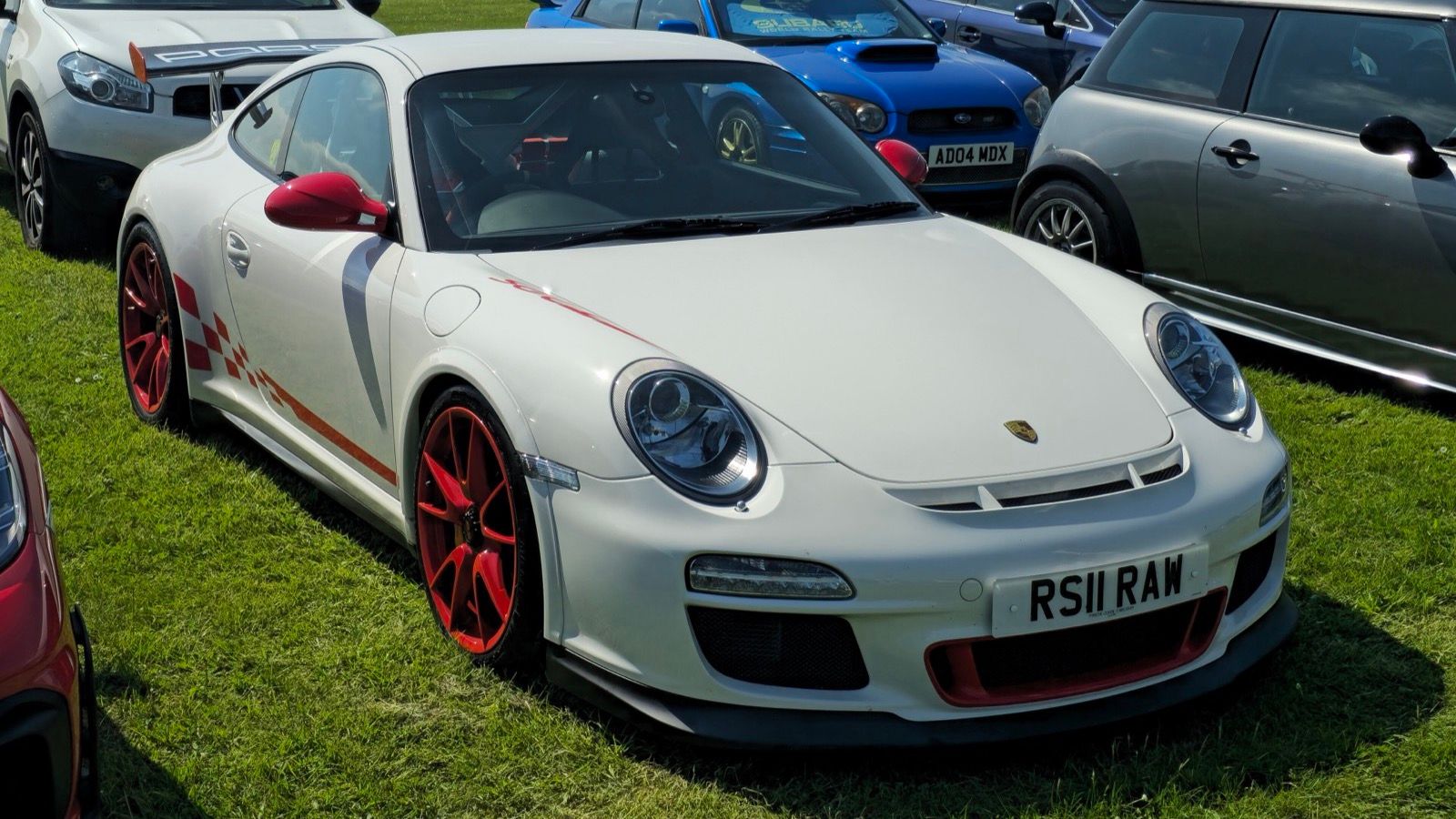 White 2011 Porsche 911 (997) GT3 RS with red wheels, front three-quarter view