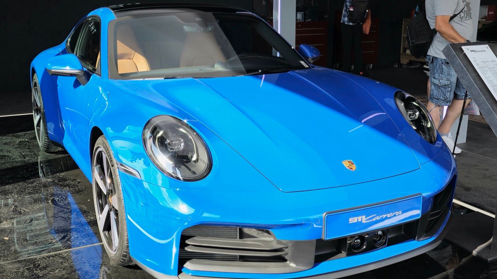 Blue 2024 Porsche 911 (992) Carrera coupe on display, front three-quarter view